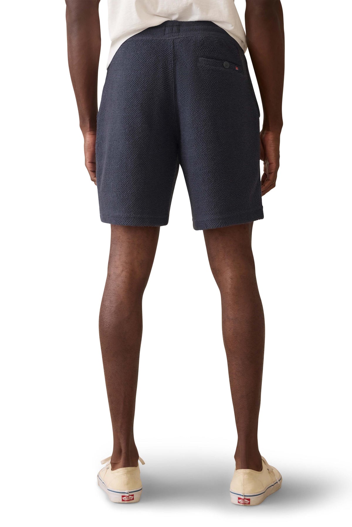 A man viewed from behind wearing navy sweat shorts and a white t-shirt, image 3 of 3