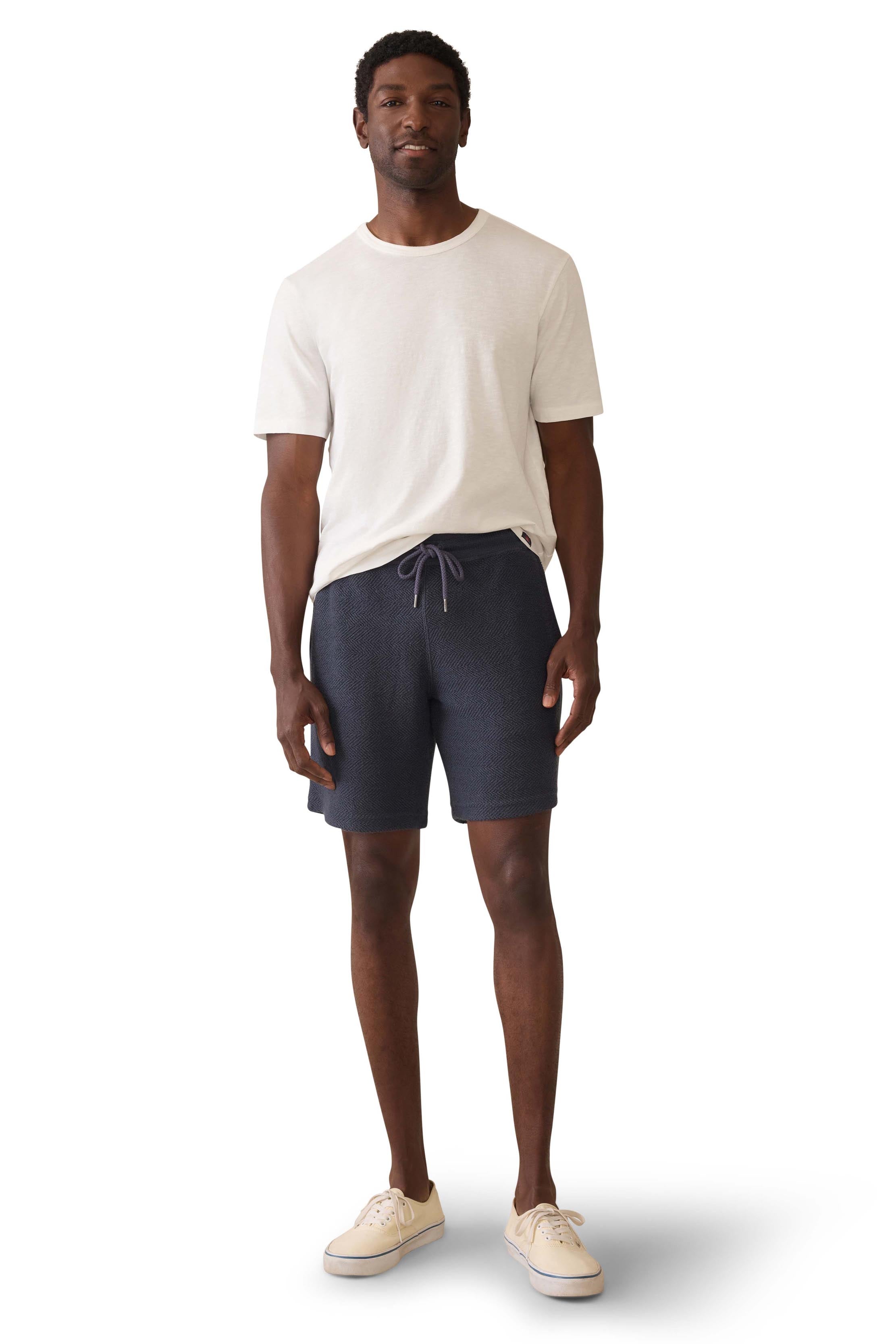 A man wearing navy sweat shorts and a white t-shirt