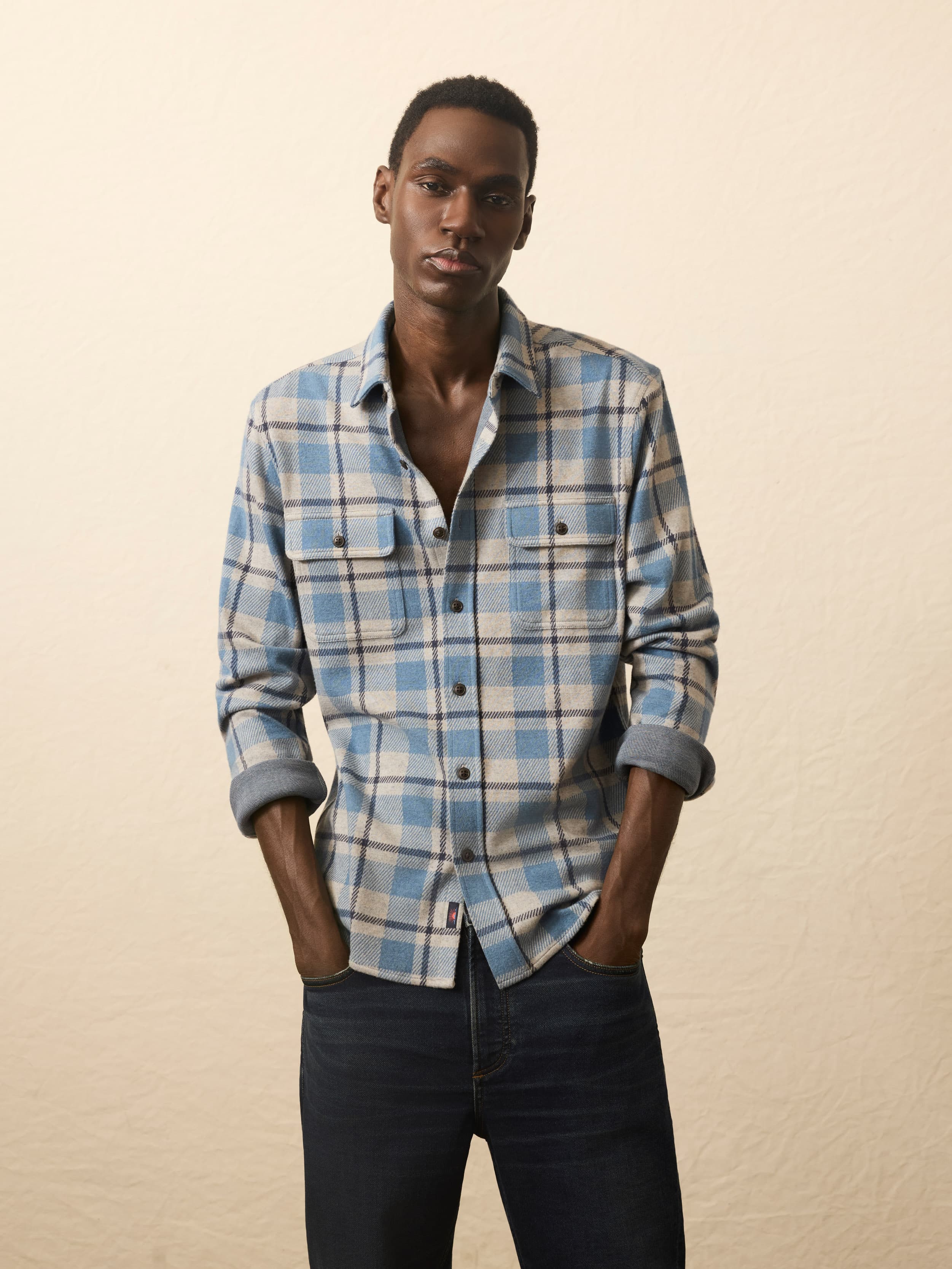 Man wearing a blue and beige plaid shirt against a beige background