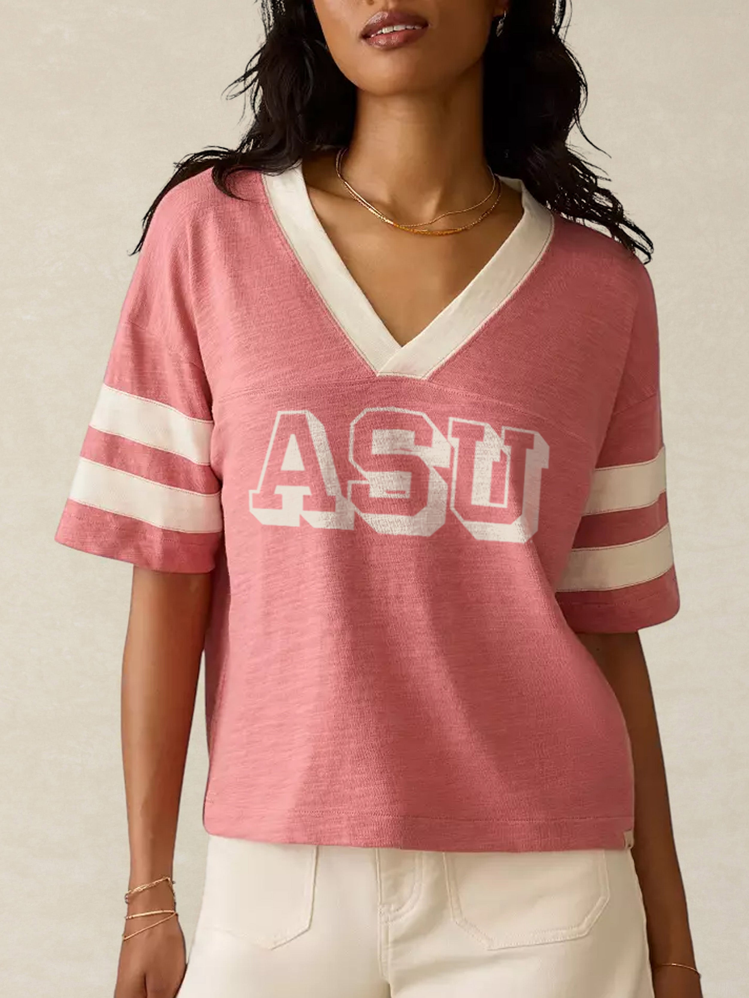 Person wearing a pink ASU t-shirt with white stripes on a neutral background