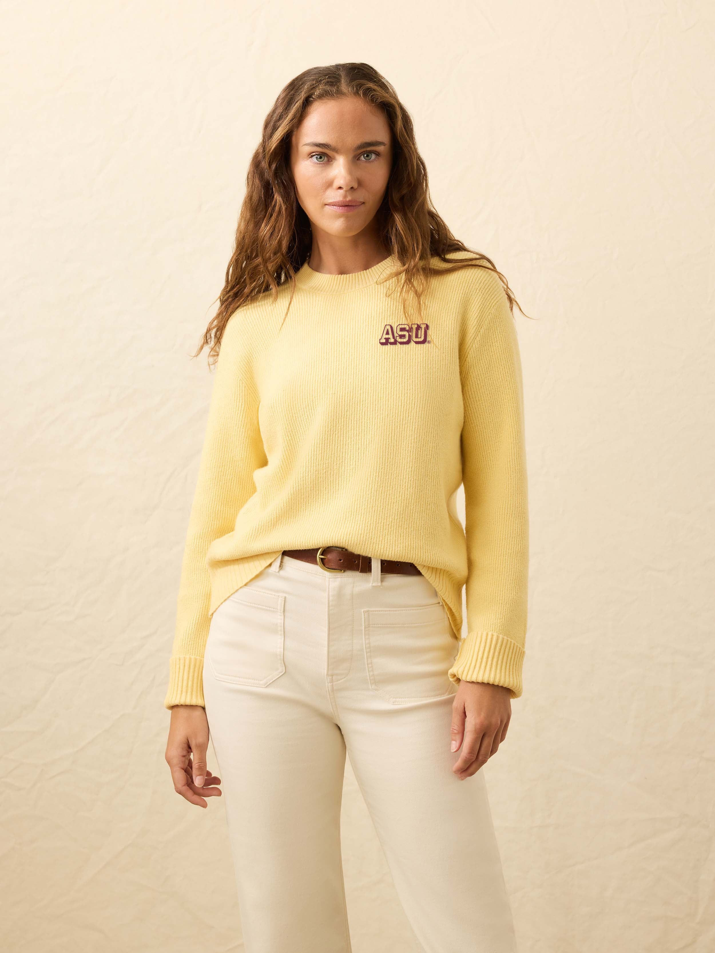 Woman wearing a yellow sweater with Arizona State University graphic on the left chest against a beige background