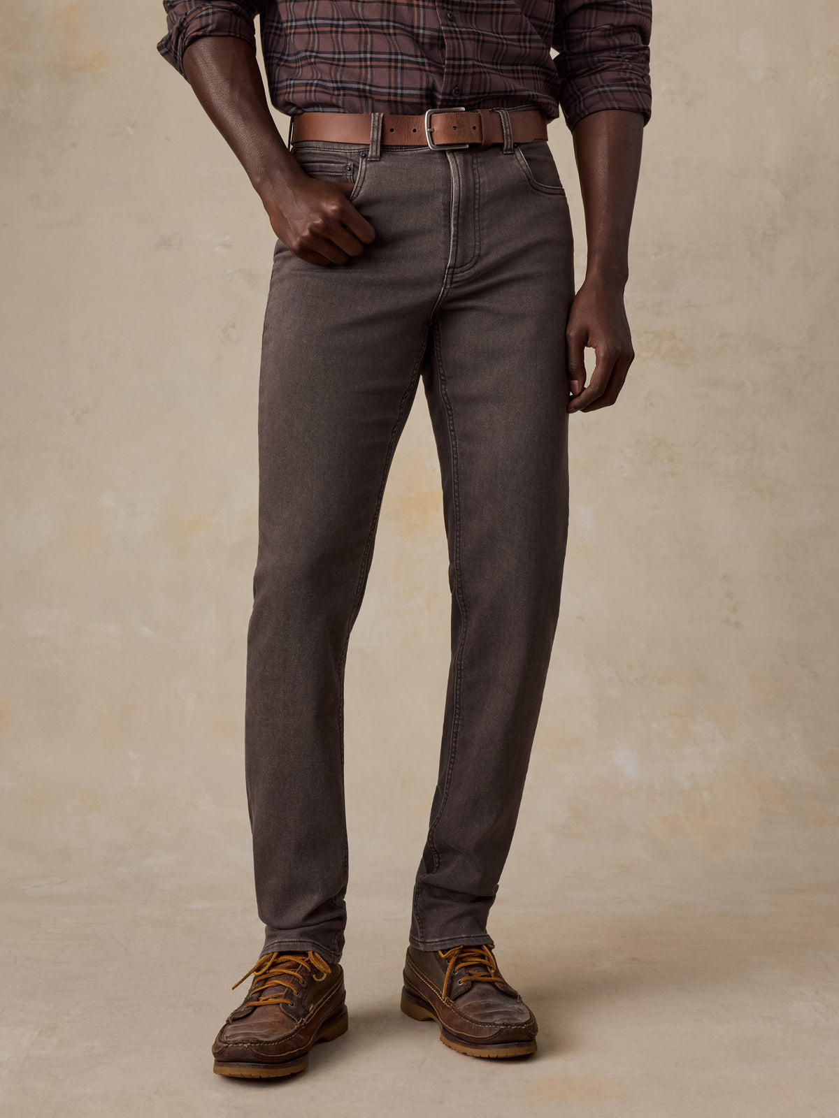 Man wearing a brown plaid shirt and brown pants, image 1 of 5