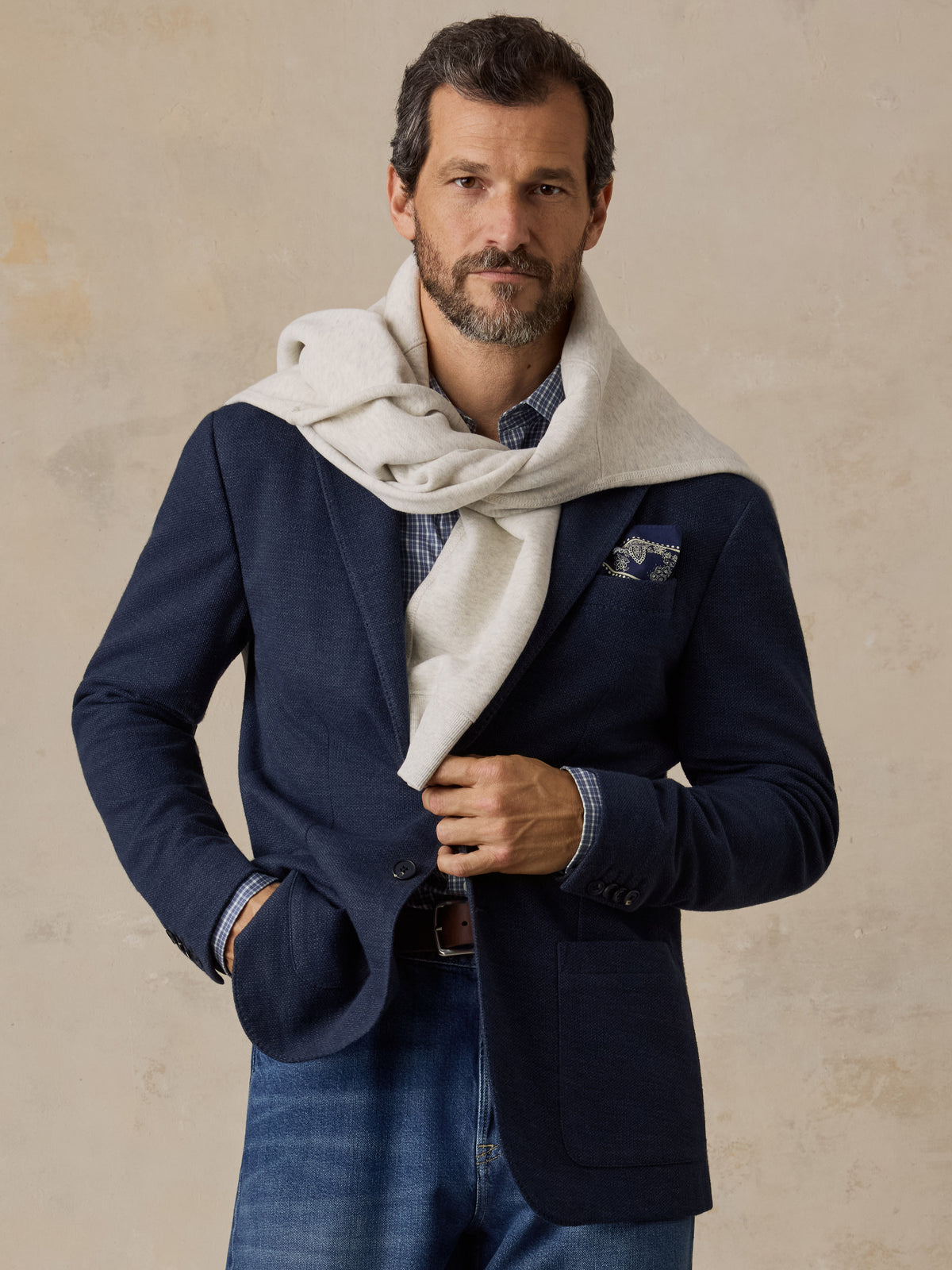 Man wearing a navy blazer over a blue button up shirt and blue jeans, image 1 of 5