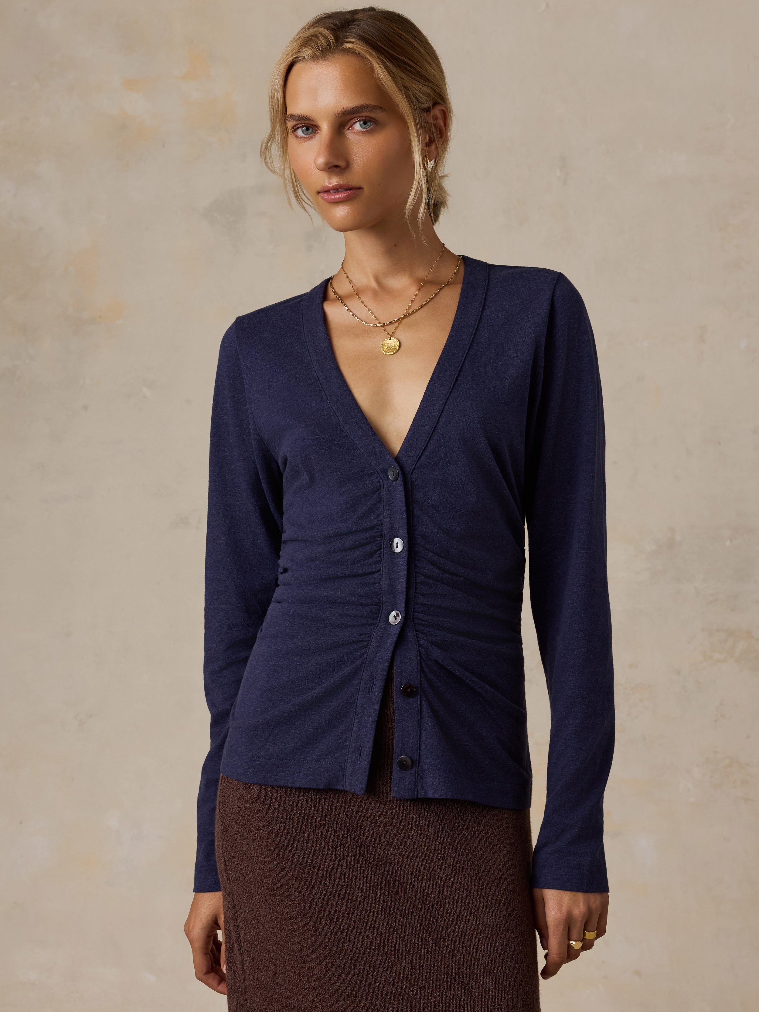 A woman wearing a blue long sleeve top and a brown skirt