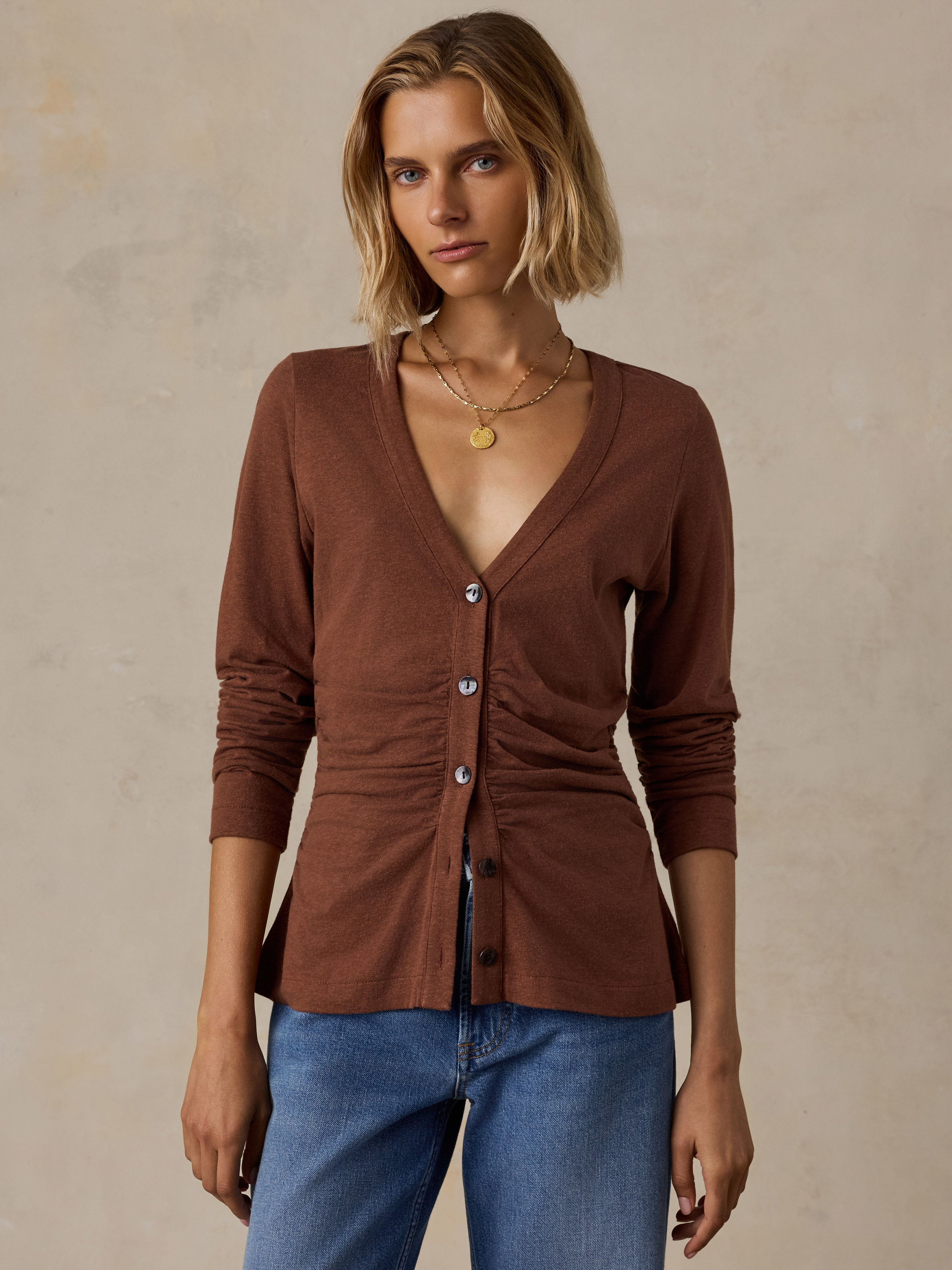 A woman wearing a brown long sleeve top and blue jeans