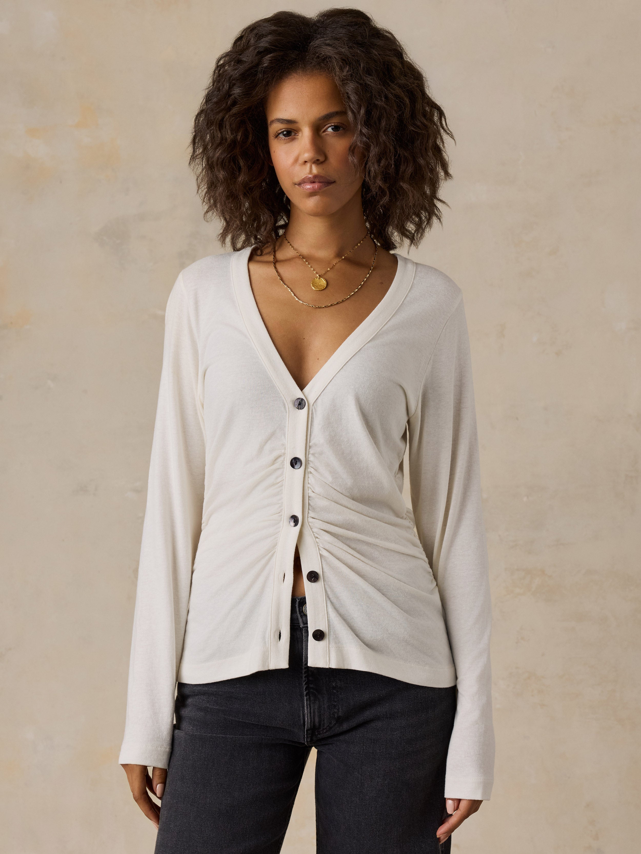 A woman wearing a white cardigan and black jeans