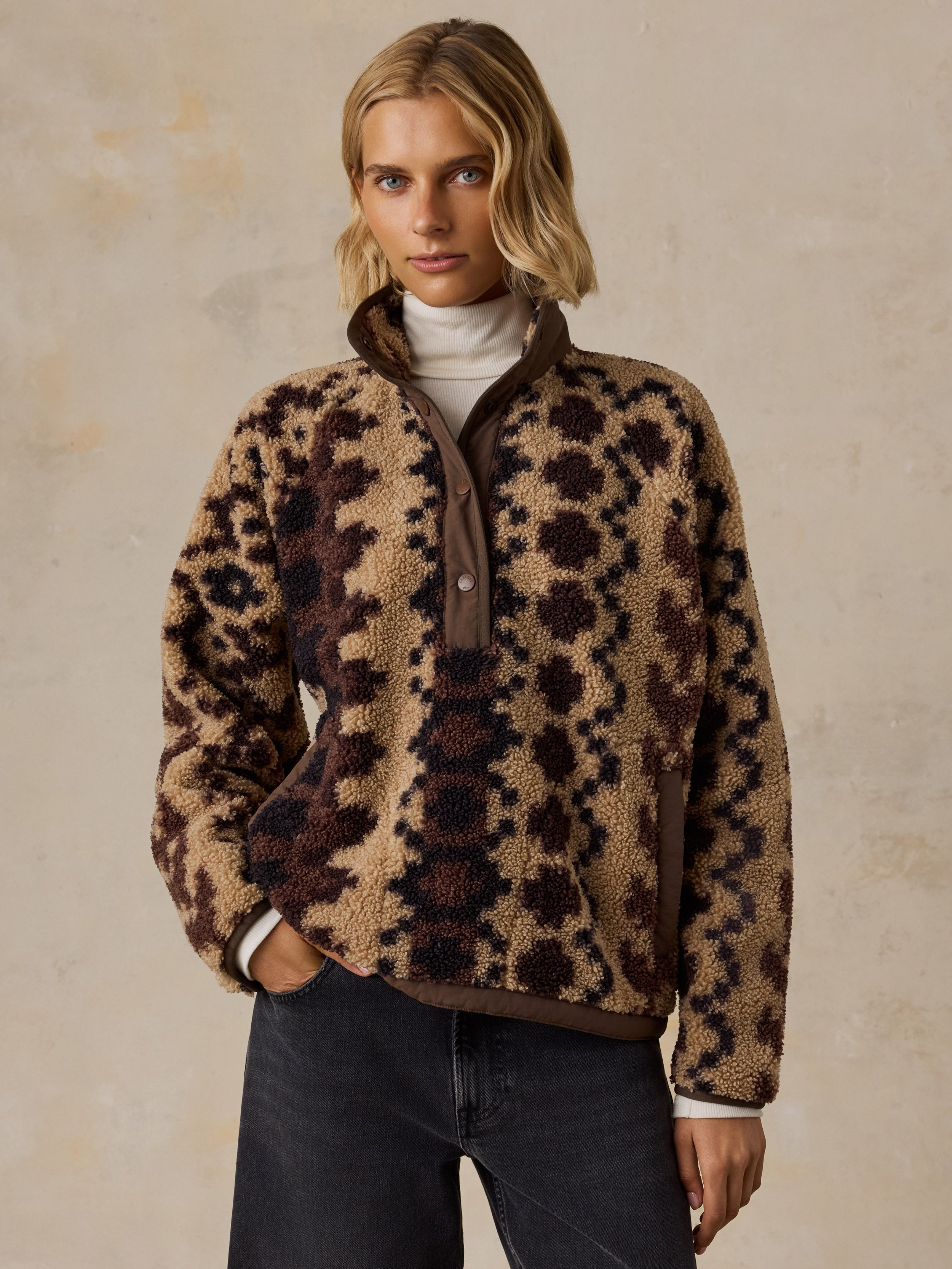 A woman wearing a brown printed fleece jacket and black jeans