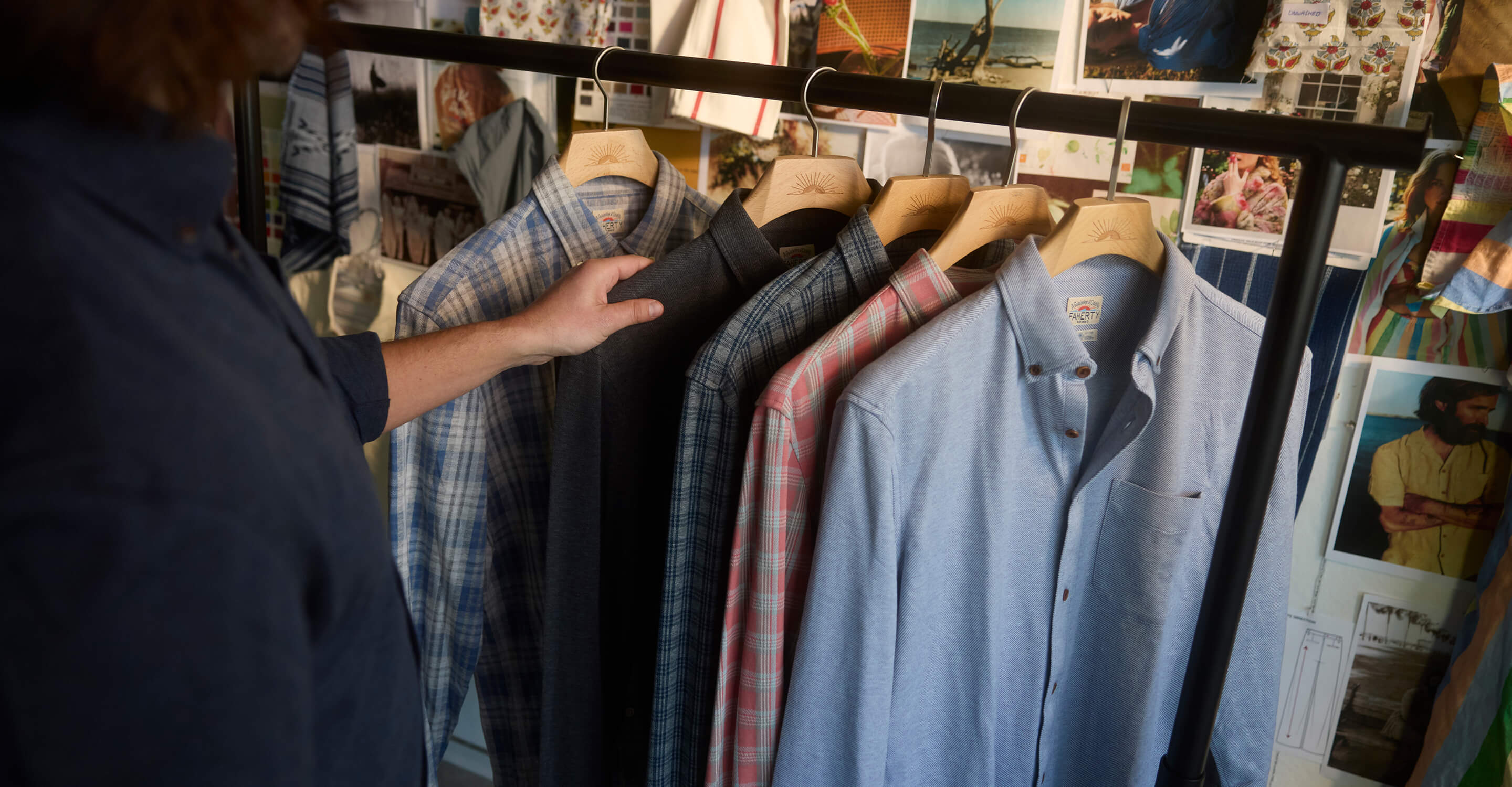Collection of coastline knit shirts hanging on a garment rack in front of a mood board