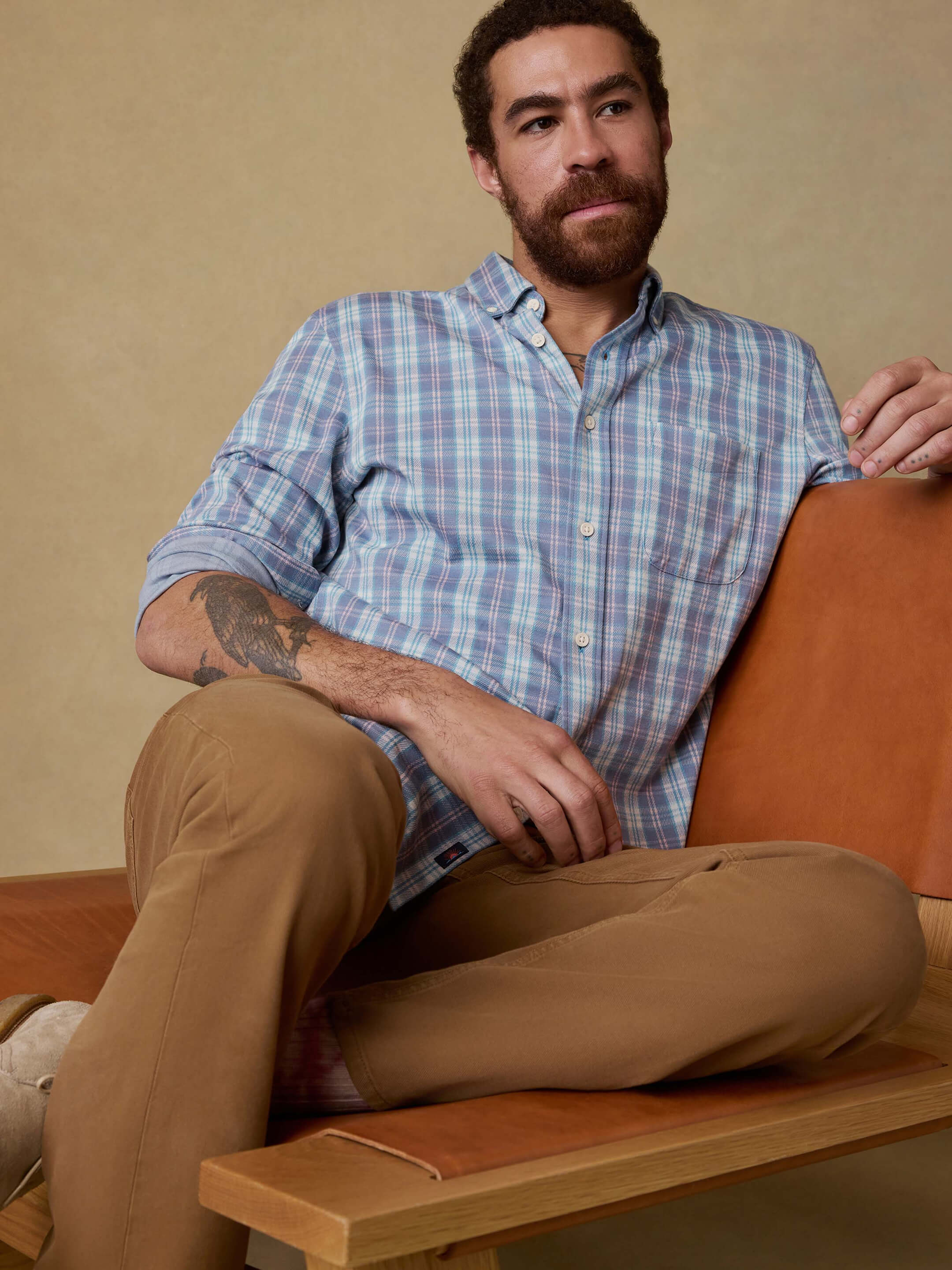 Male model posed on a modernist chair wearing a coastline knit shirt