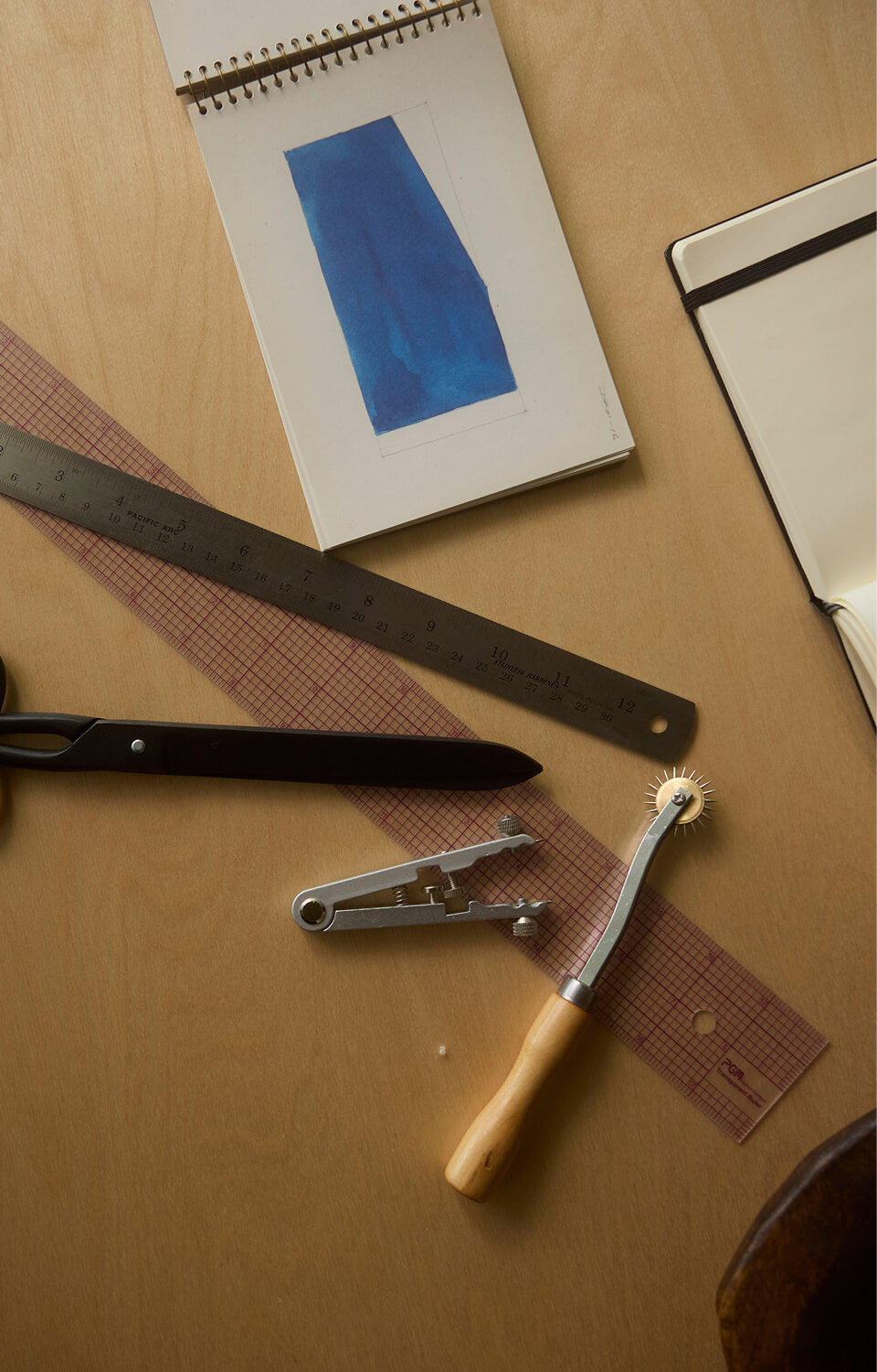overhead of apparel design instruments and sketchbooks on a table