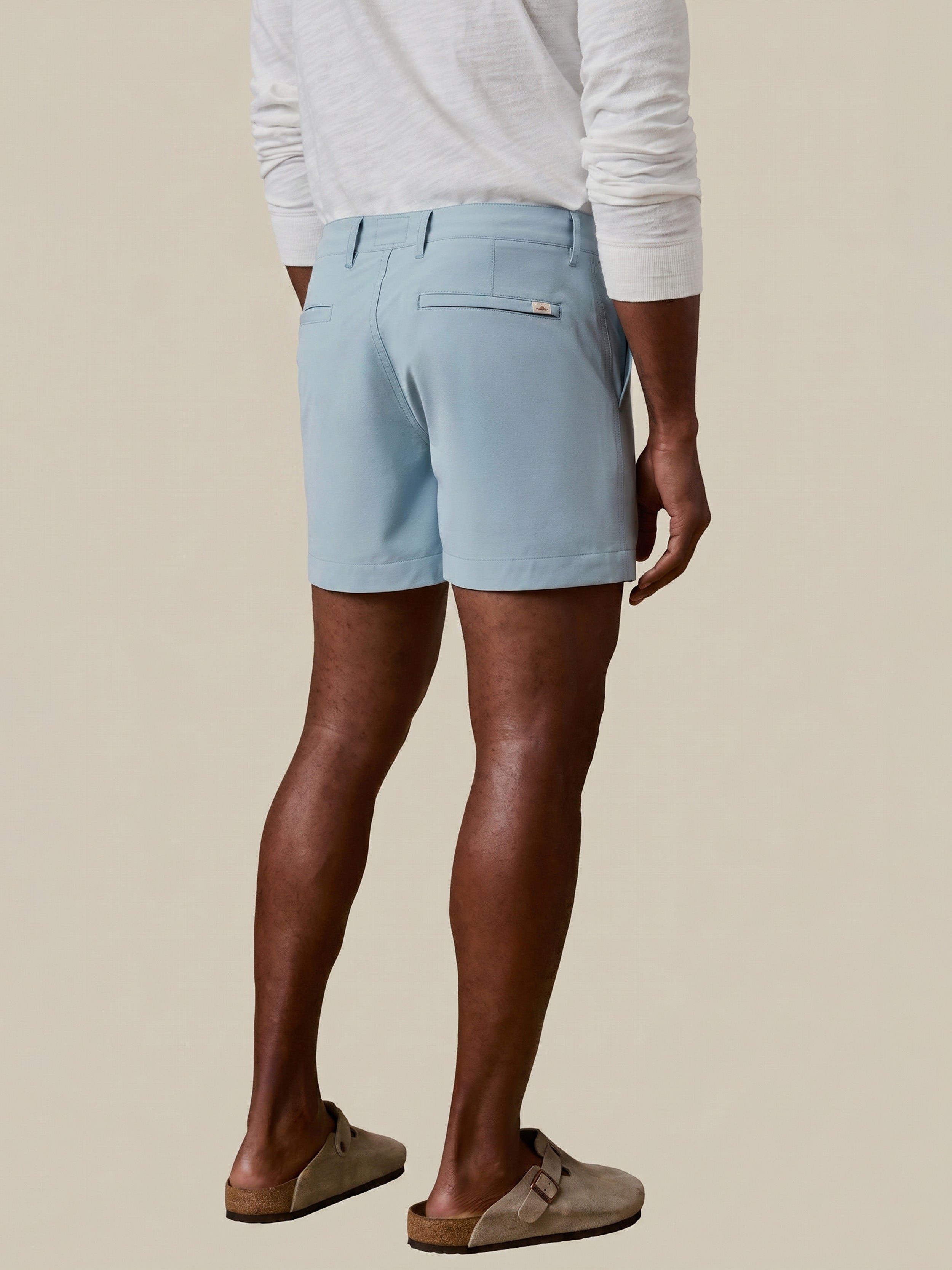 Man wearing light blue shorts on a beige background