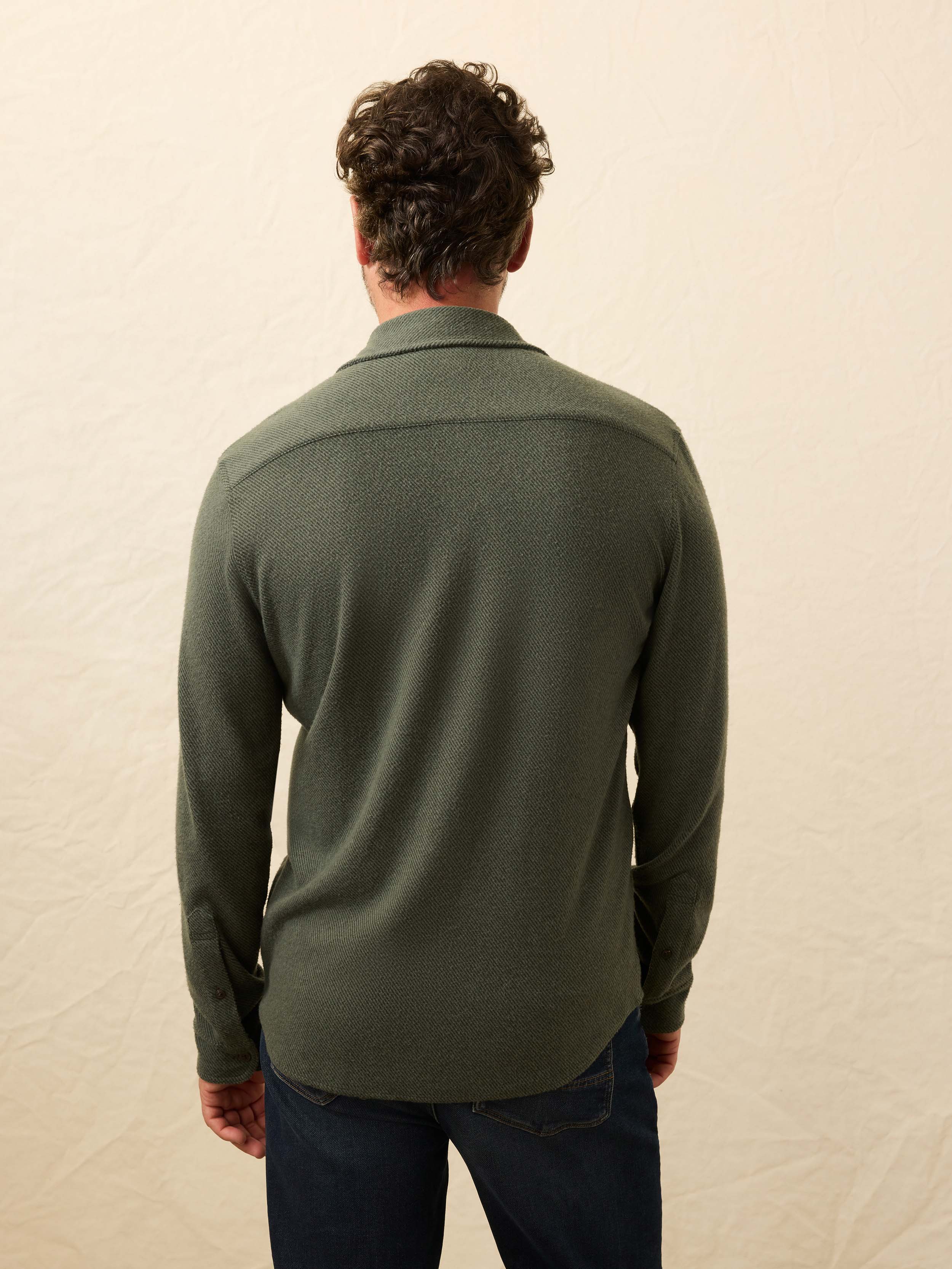 Man wearing a green shirt against a beige background
