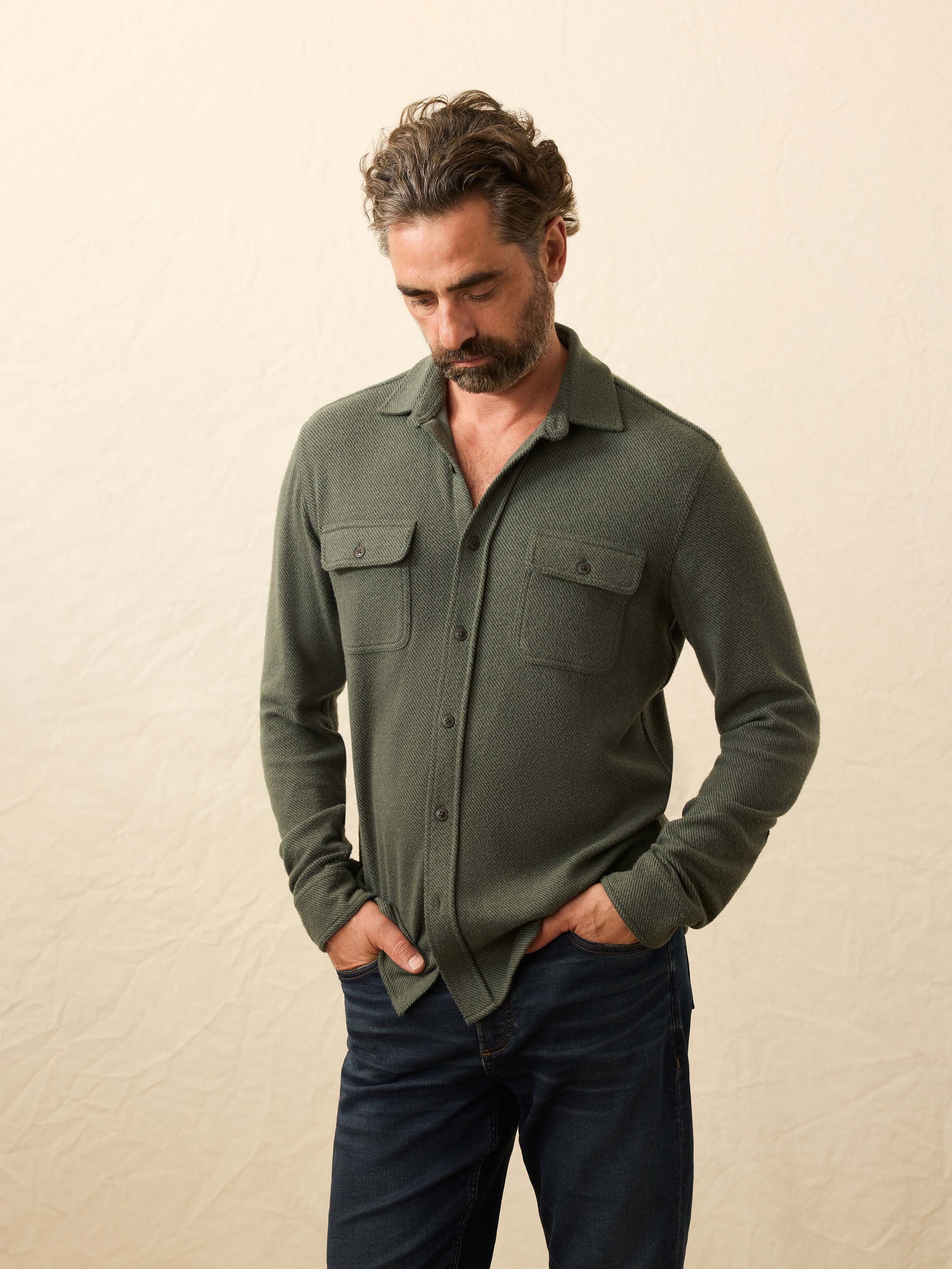 Man wearing a green shirt with long sleeves against a beige background