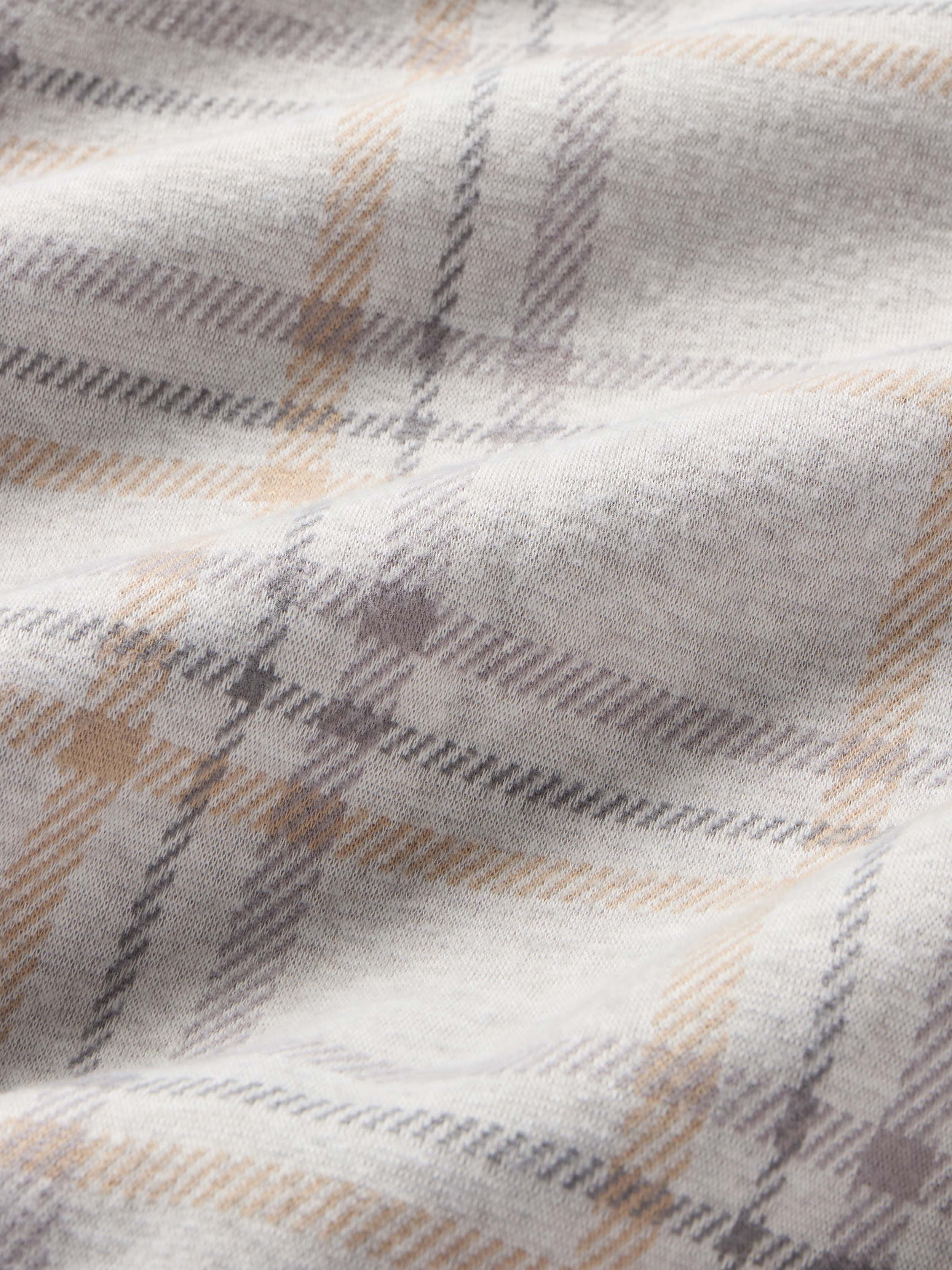 Close-up of a plaid blanket with light blue, beige, and gray color