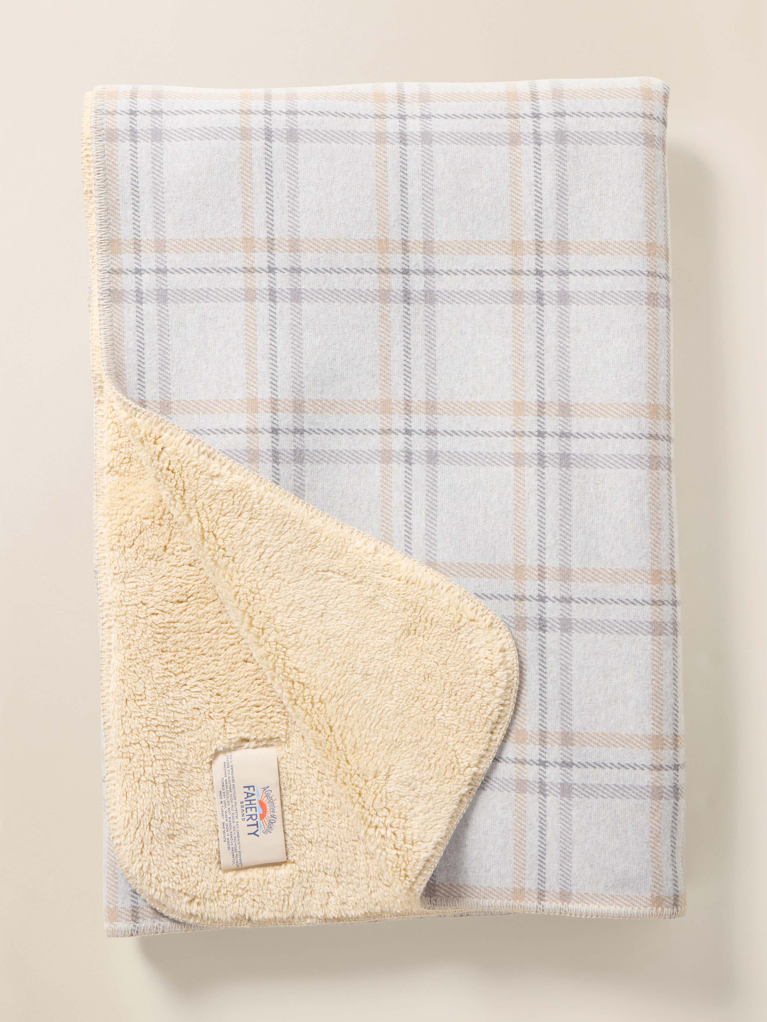 Light blue plaid blanket with cream-colored fleece on a beige background
