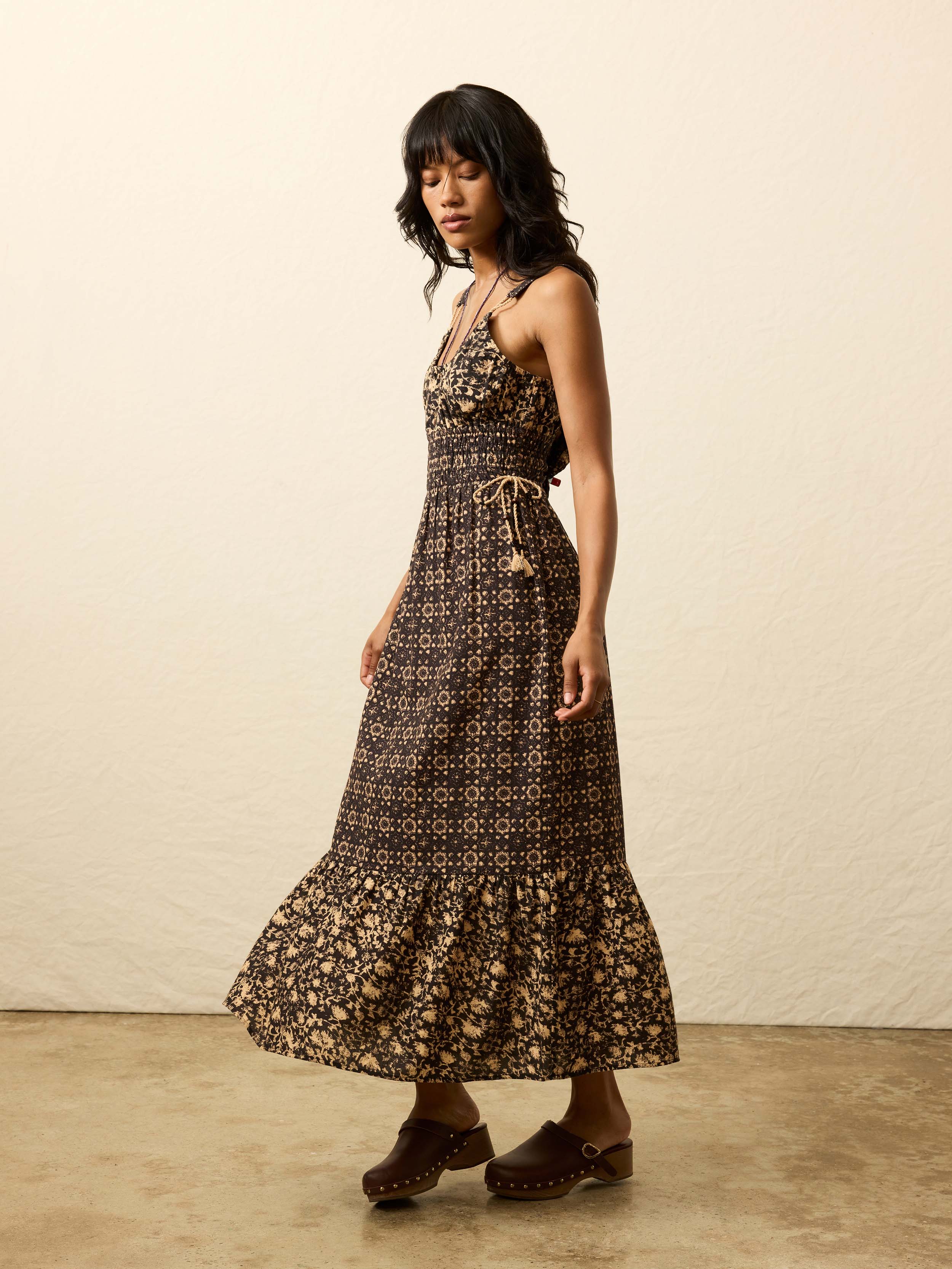 Woman is wearing a patterned dress against a beige background
