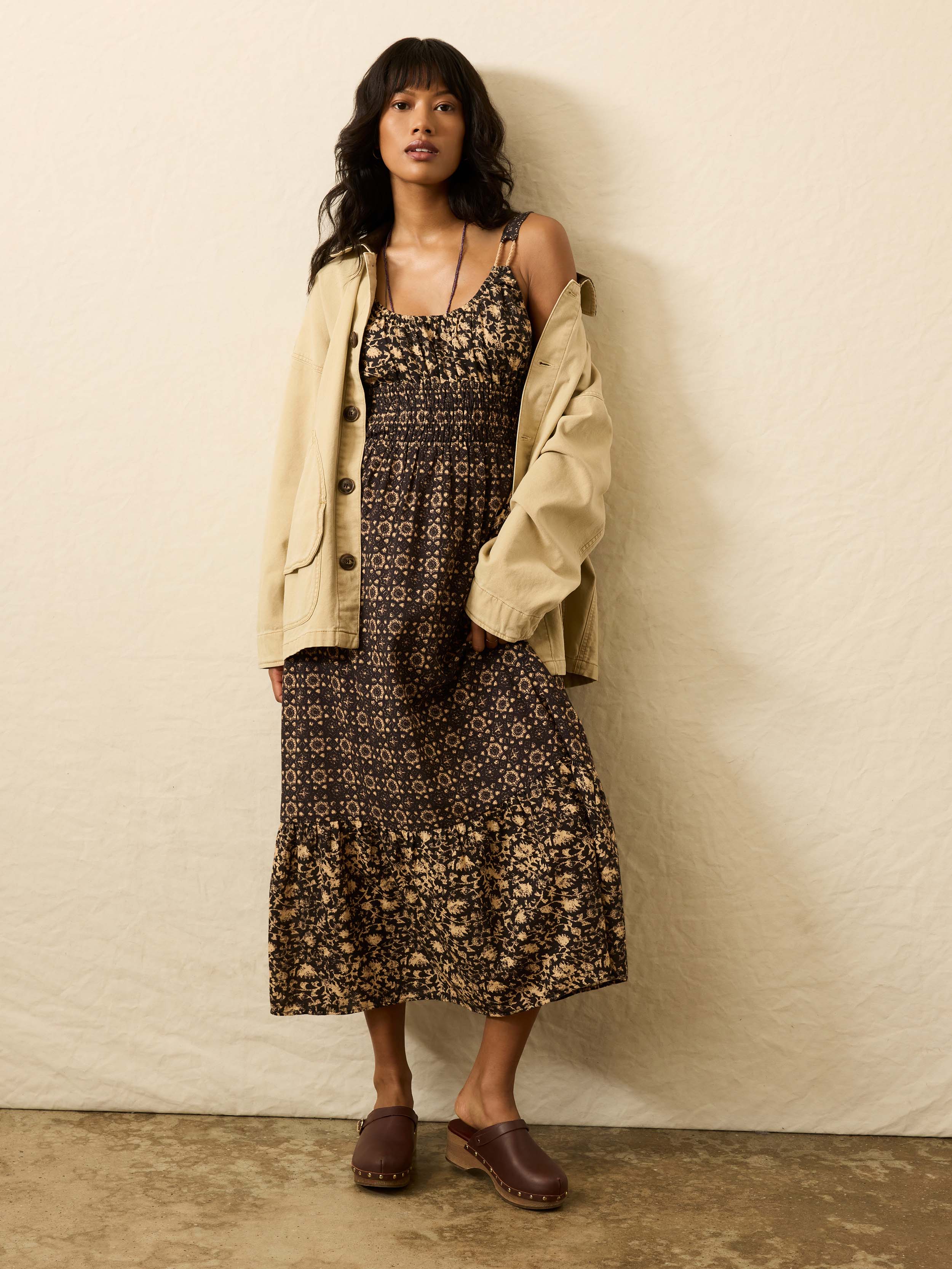 Woman is wearing a patterned dress against a beige background