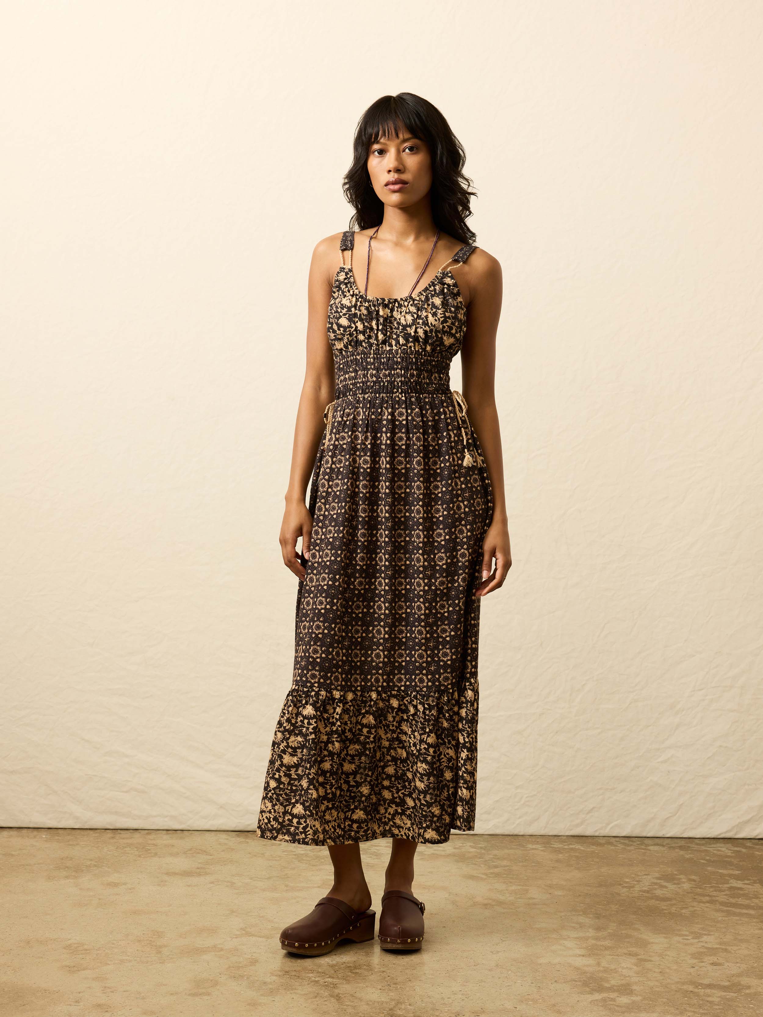 Woman is wearing a patterned dress against a beige background
