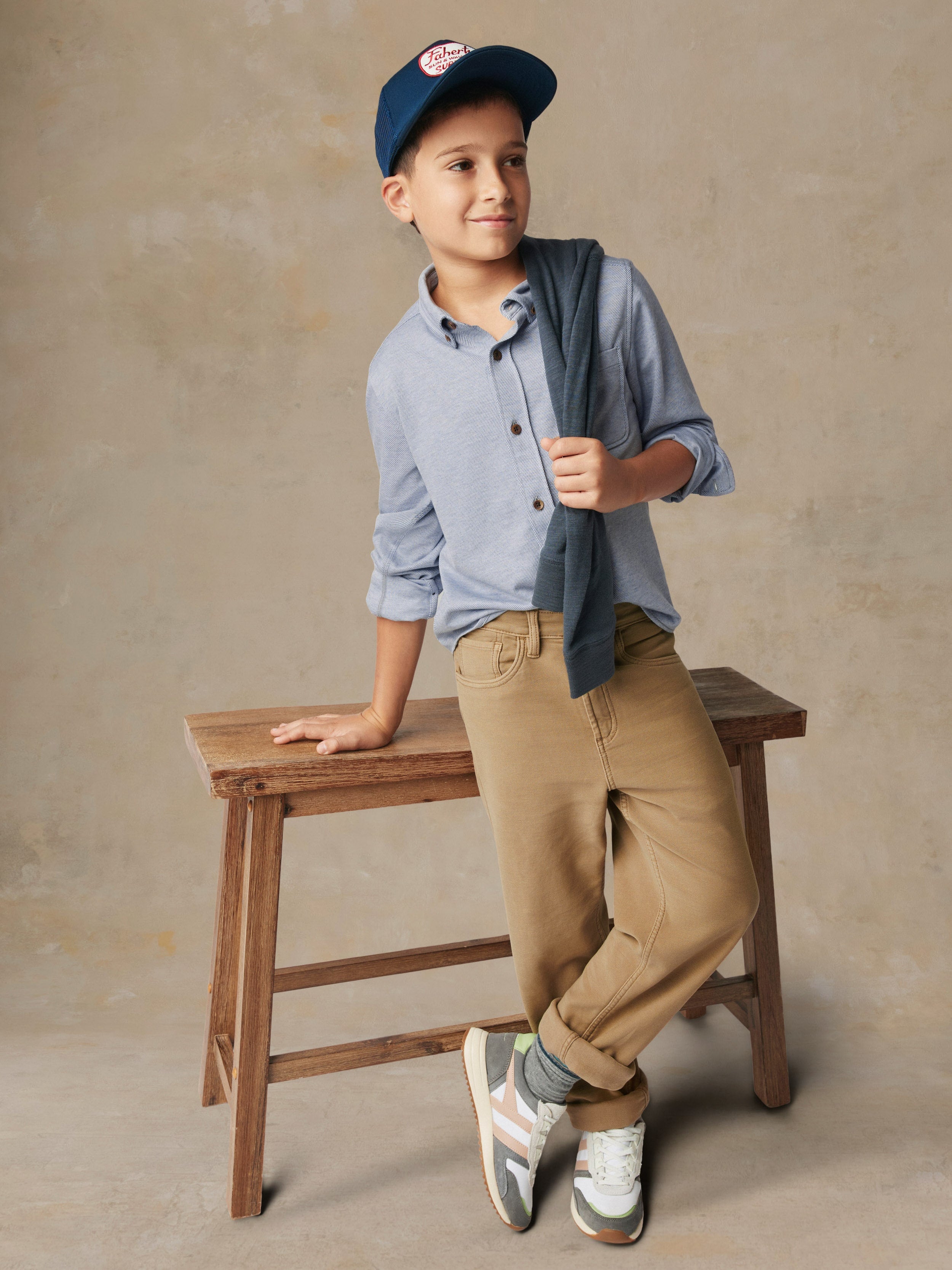 A child wearing a blue button up shirt and beige pants