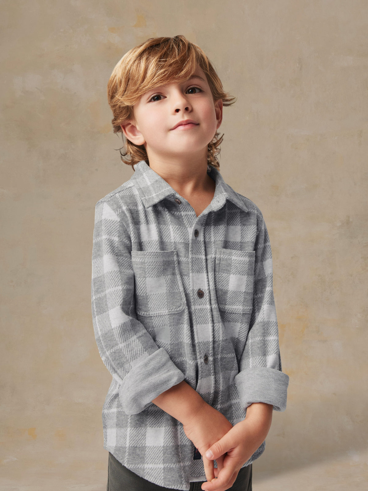 Close up of a child wearing a grey plaid button up shirt and grey pants, image 5 of 6