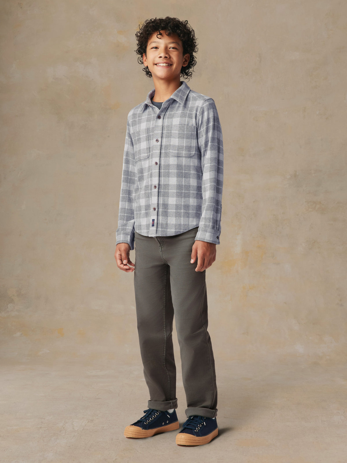 A child wearing a grey plaid button up shirt and grey pants, image 3 of 7