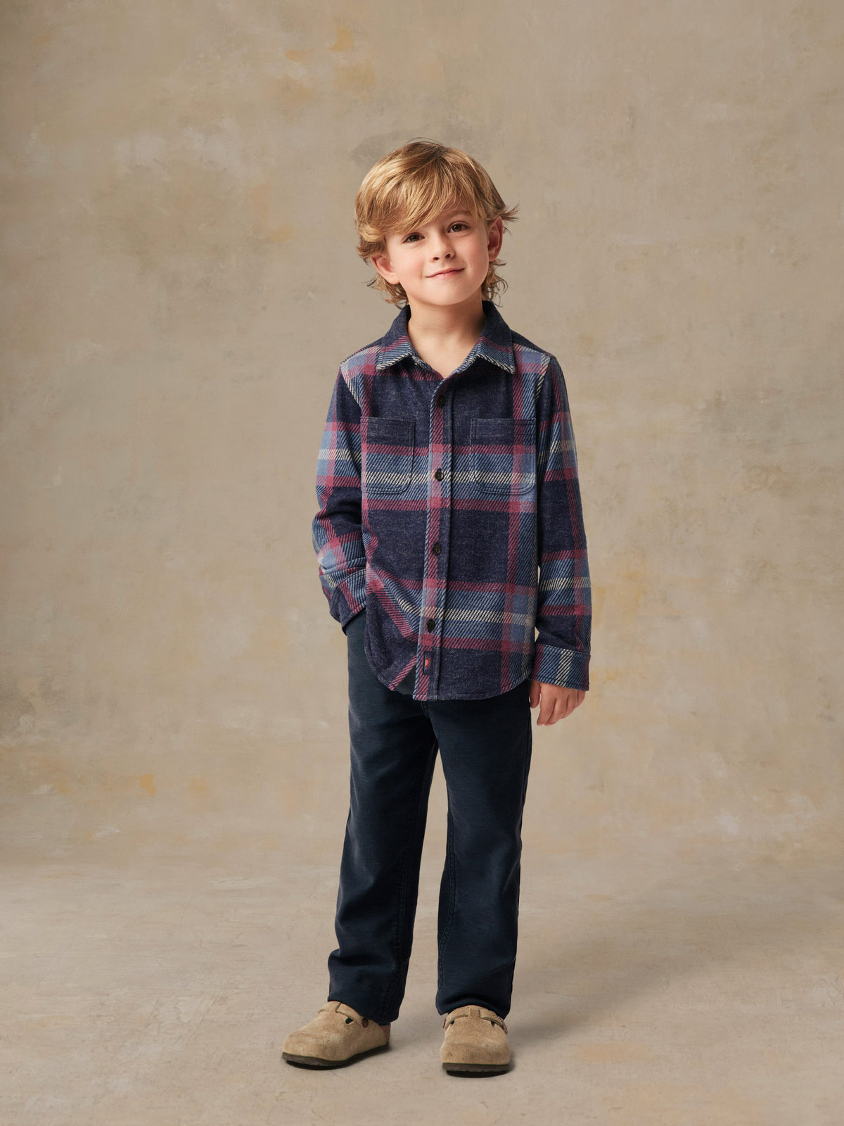 A child wearing a plaid shirt and black pants, image 5 of 6