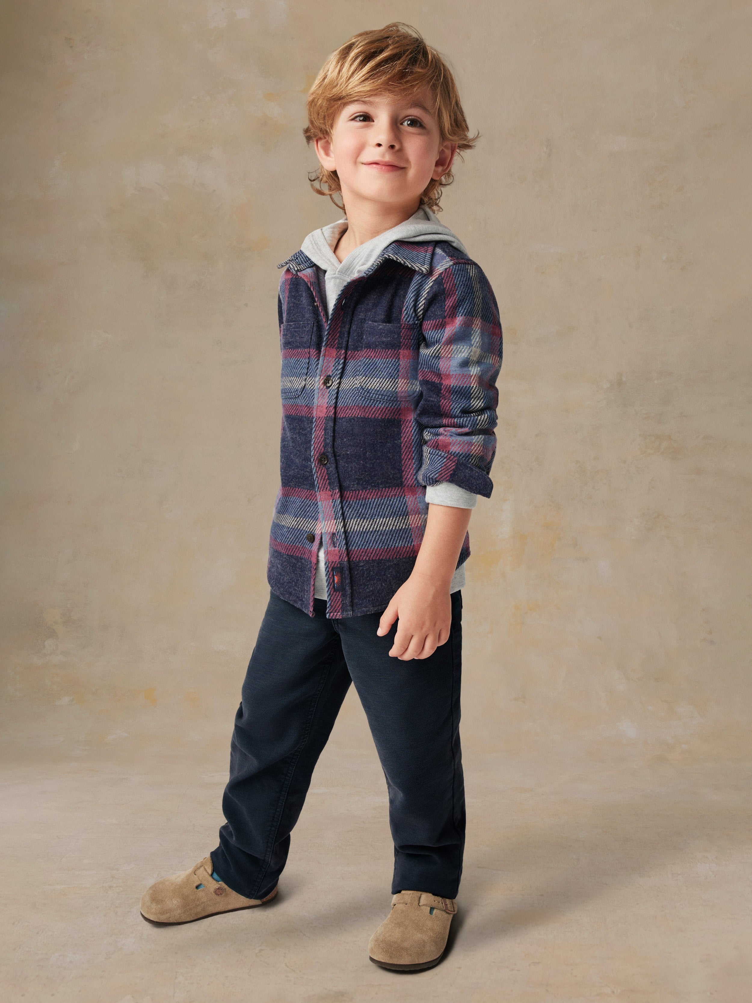 A child wearing a plaid shirt and black pants