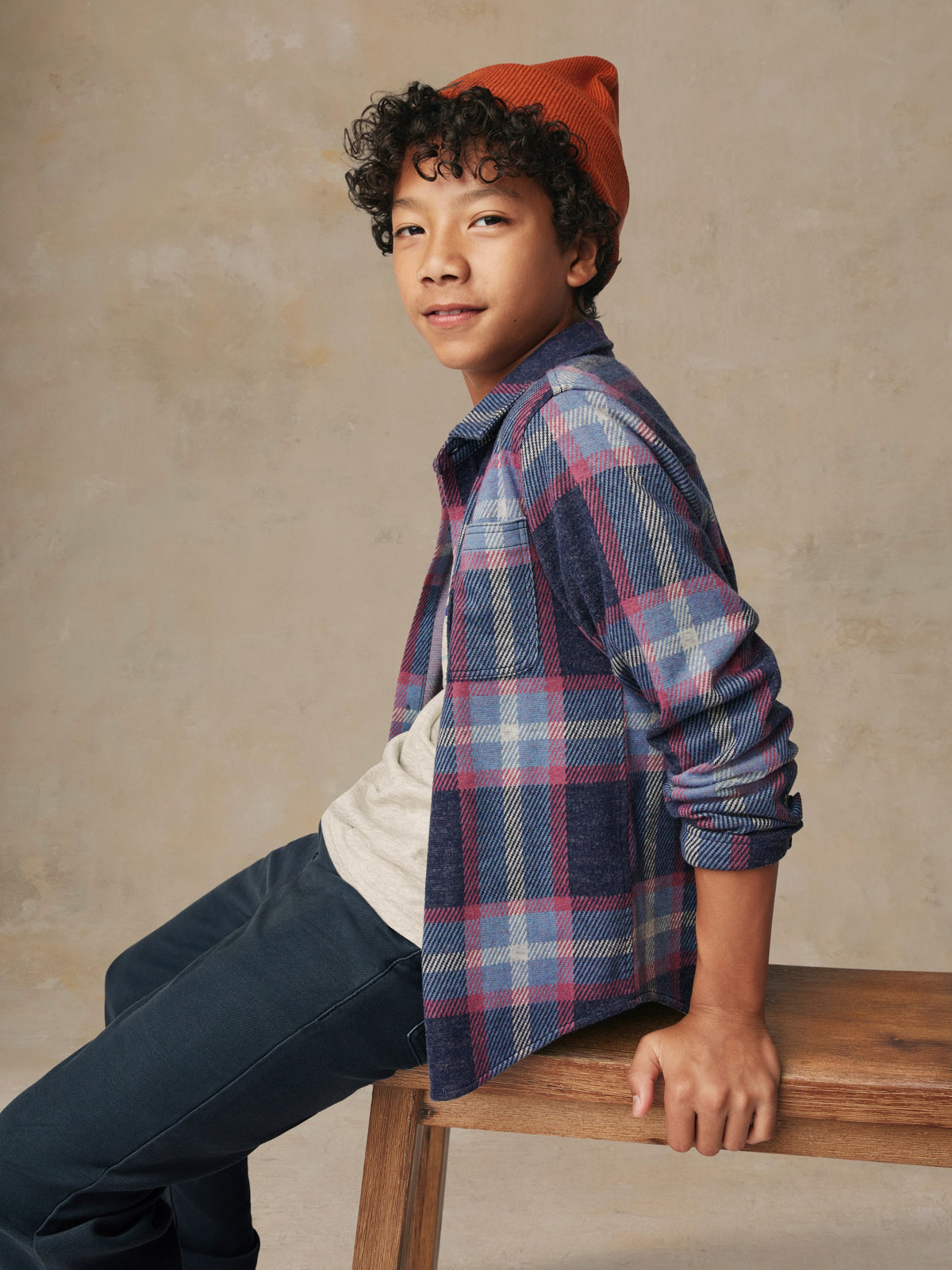 Close up of a child wearing a plaid button up shirt and black pants, image 2 of 6