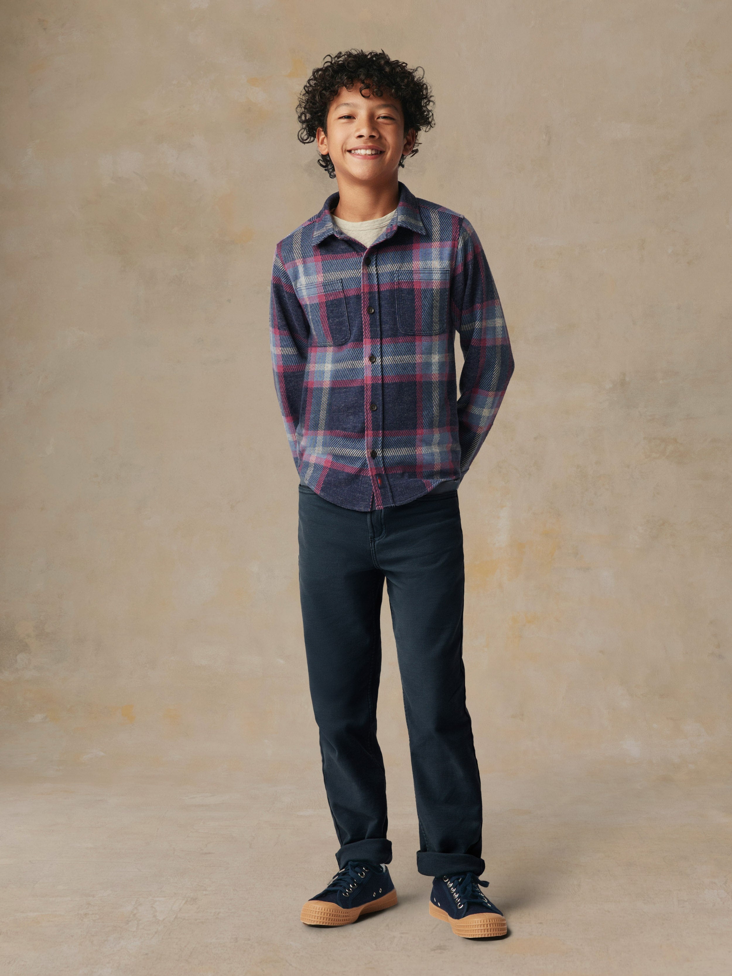 A child wearing a plaid button up shirt and black pants