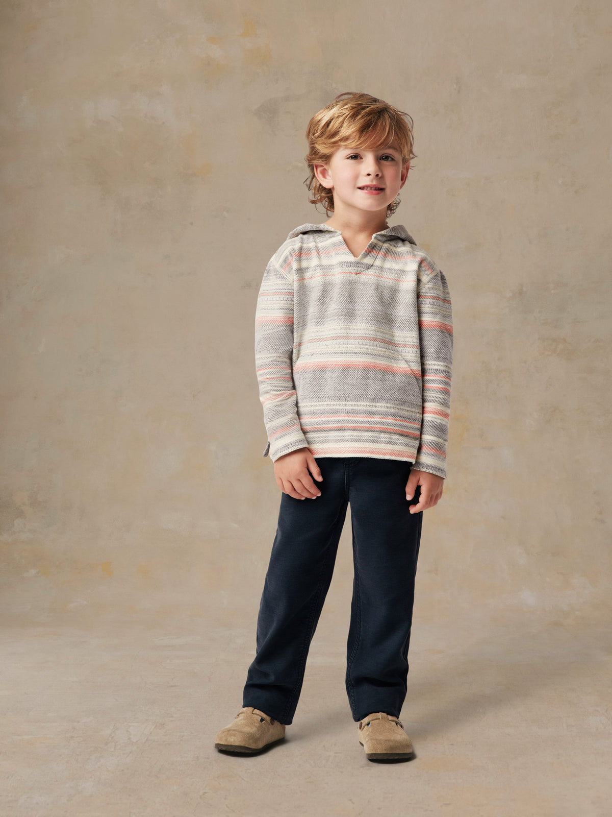 A boy wearing a striped hoodie and blue pants, image 1 of 4