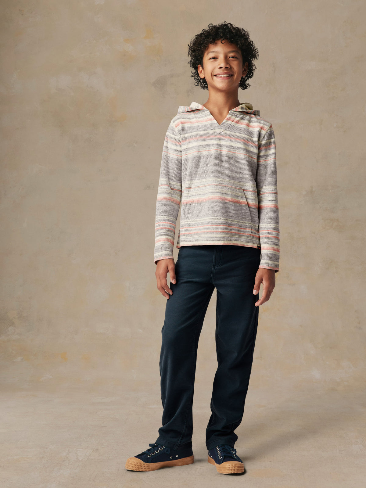 A kid wearing a striped hoodie and blue pants, image 1 of 5