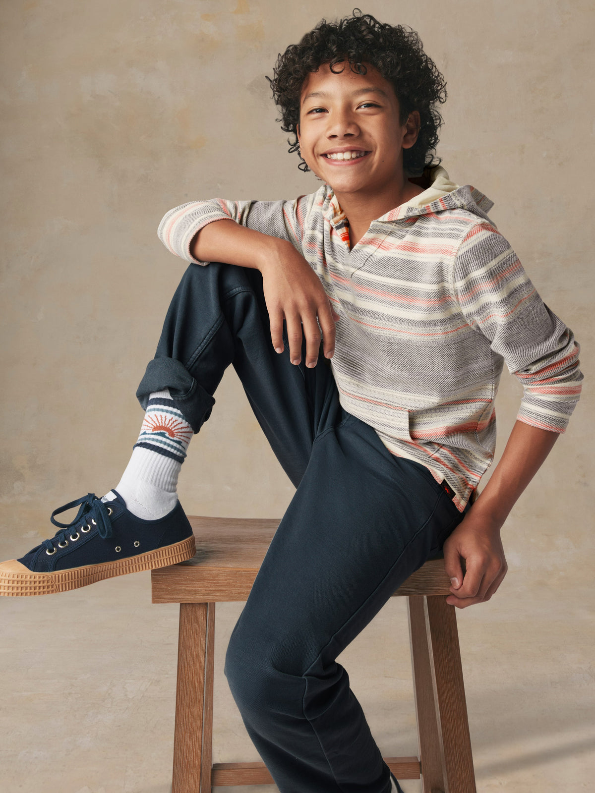 A kid wearing a striped hoodie and blue pants, image 5 of 5