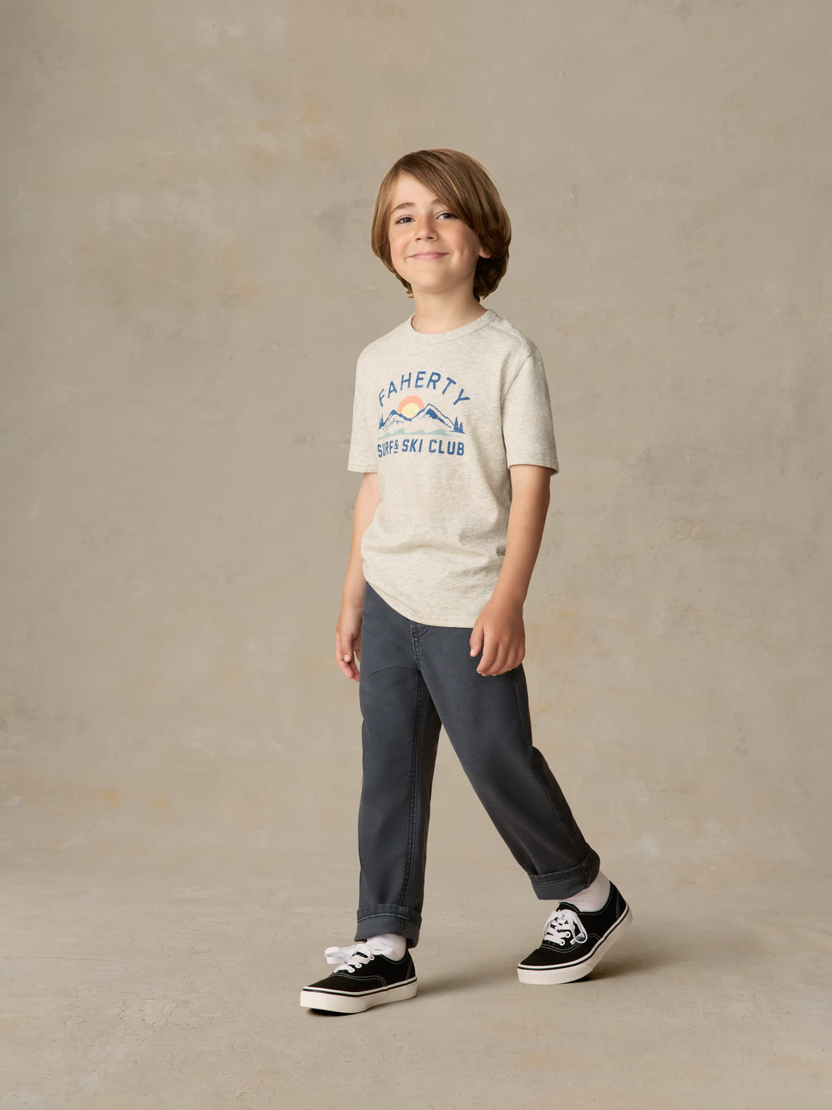 Child wearing graphic grey tee and navy pants against a beige background, image 1 of 6