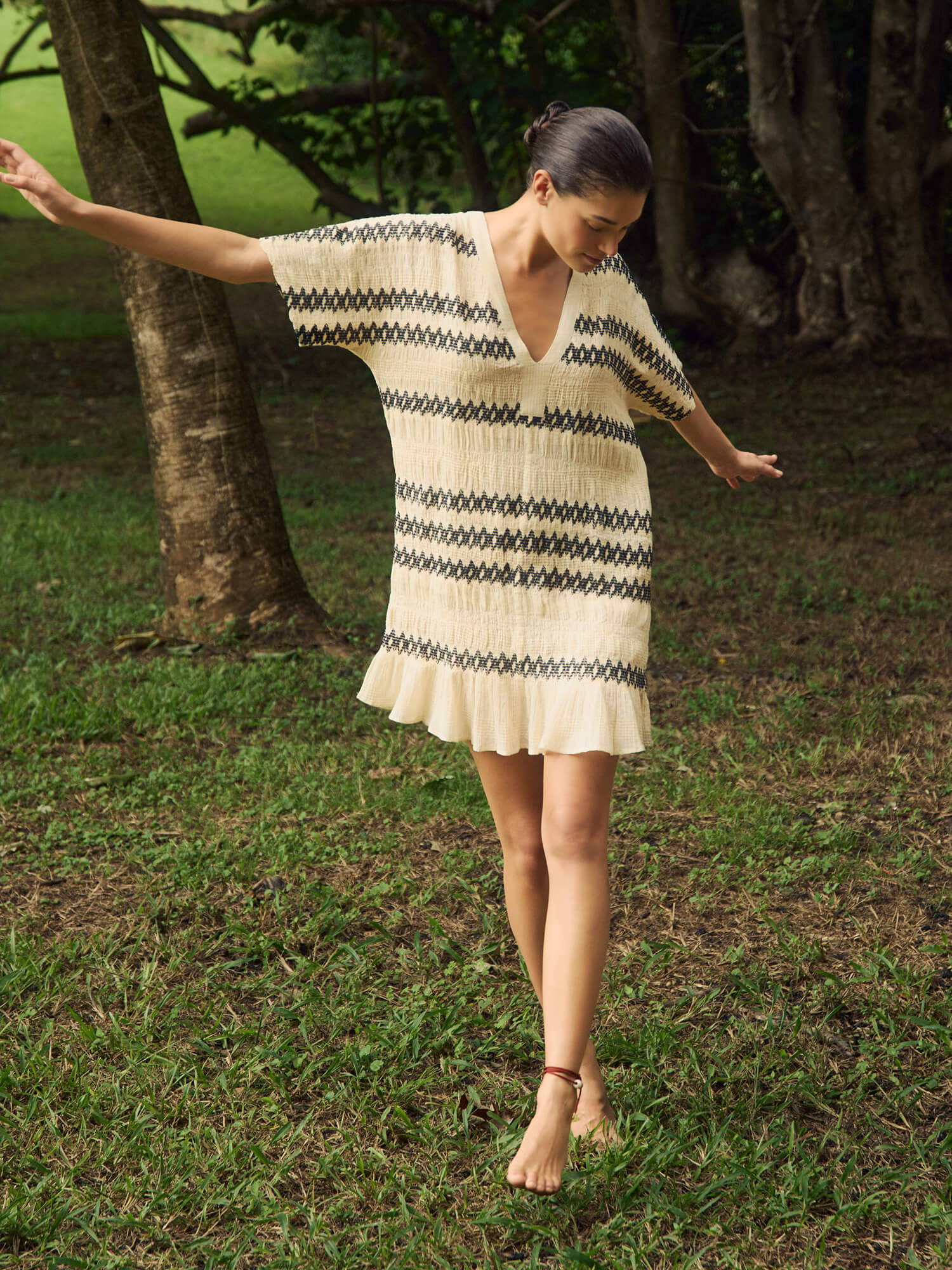 Woman wearing a blue and white striped mini dress in a forest setting.