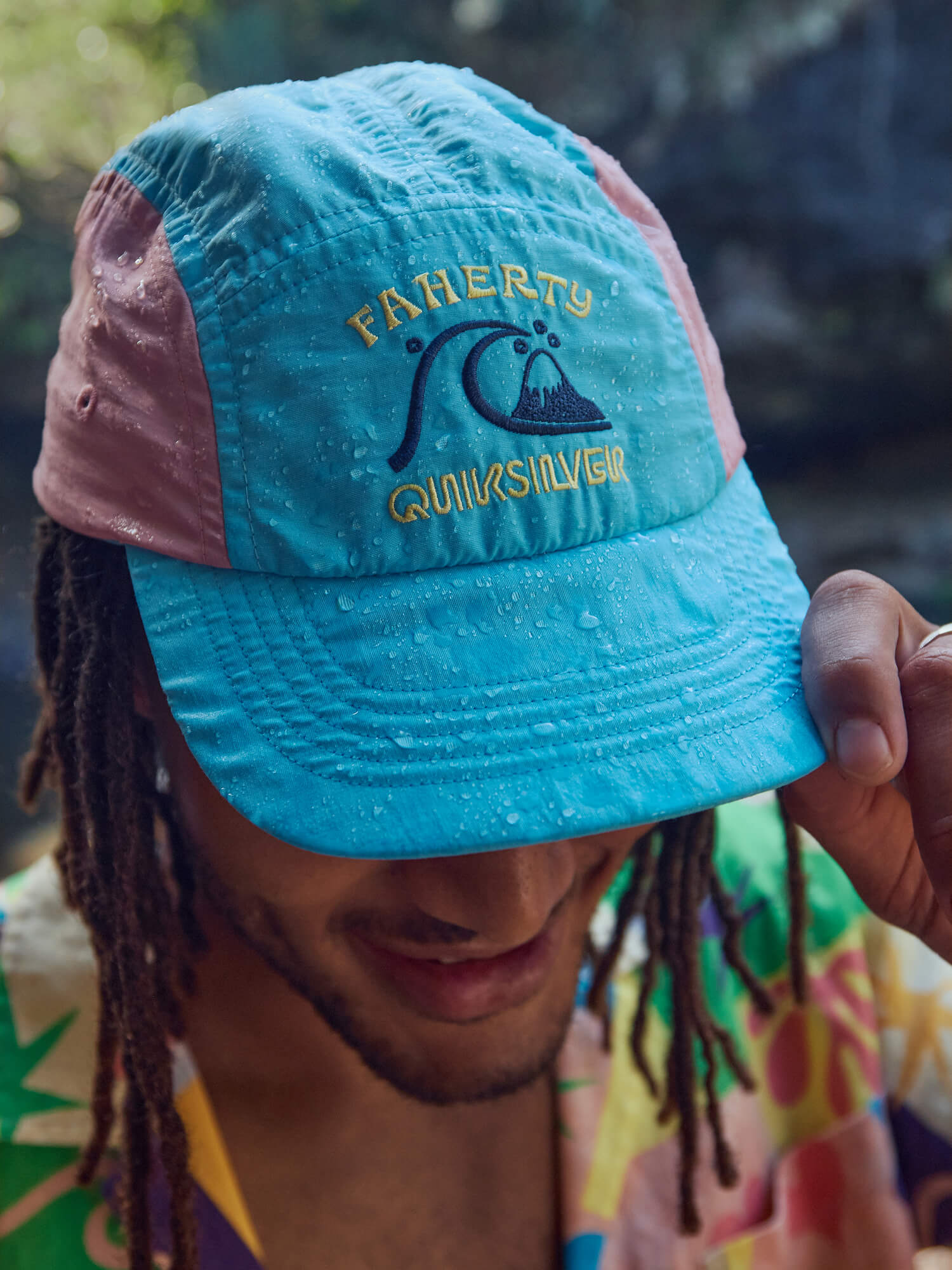 Man wearing a blue and pink cap with 'Faherty' and 'Quiksilver' logos on the front.