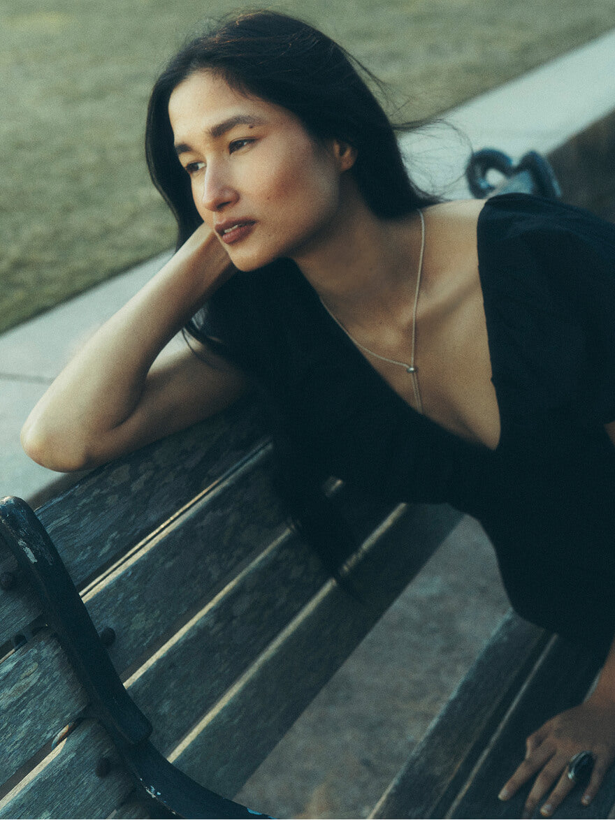 A woman in a black dress sitting on a park bench