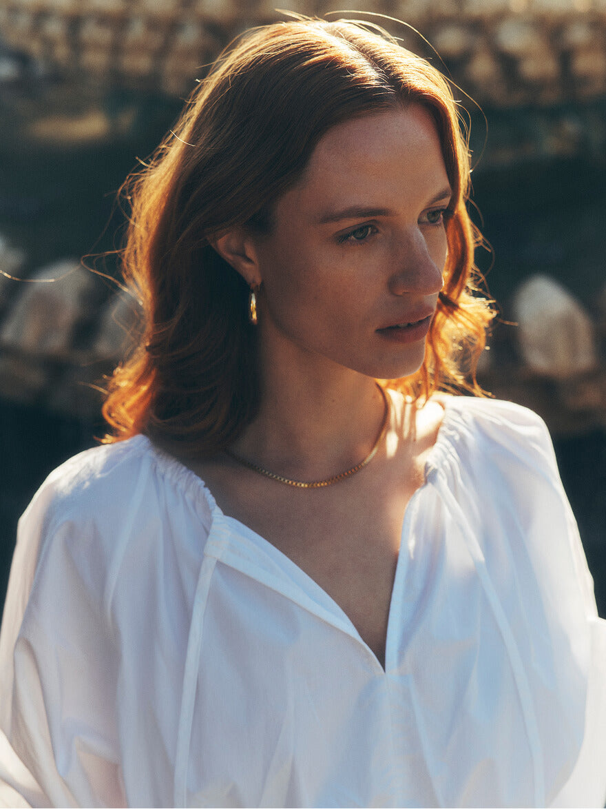 Woman in a white blouse with the setting sun lighting her face