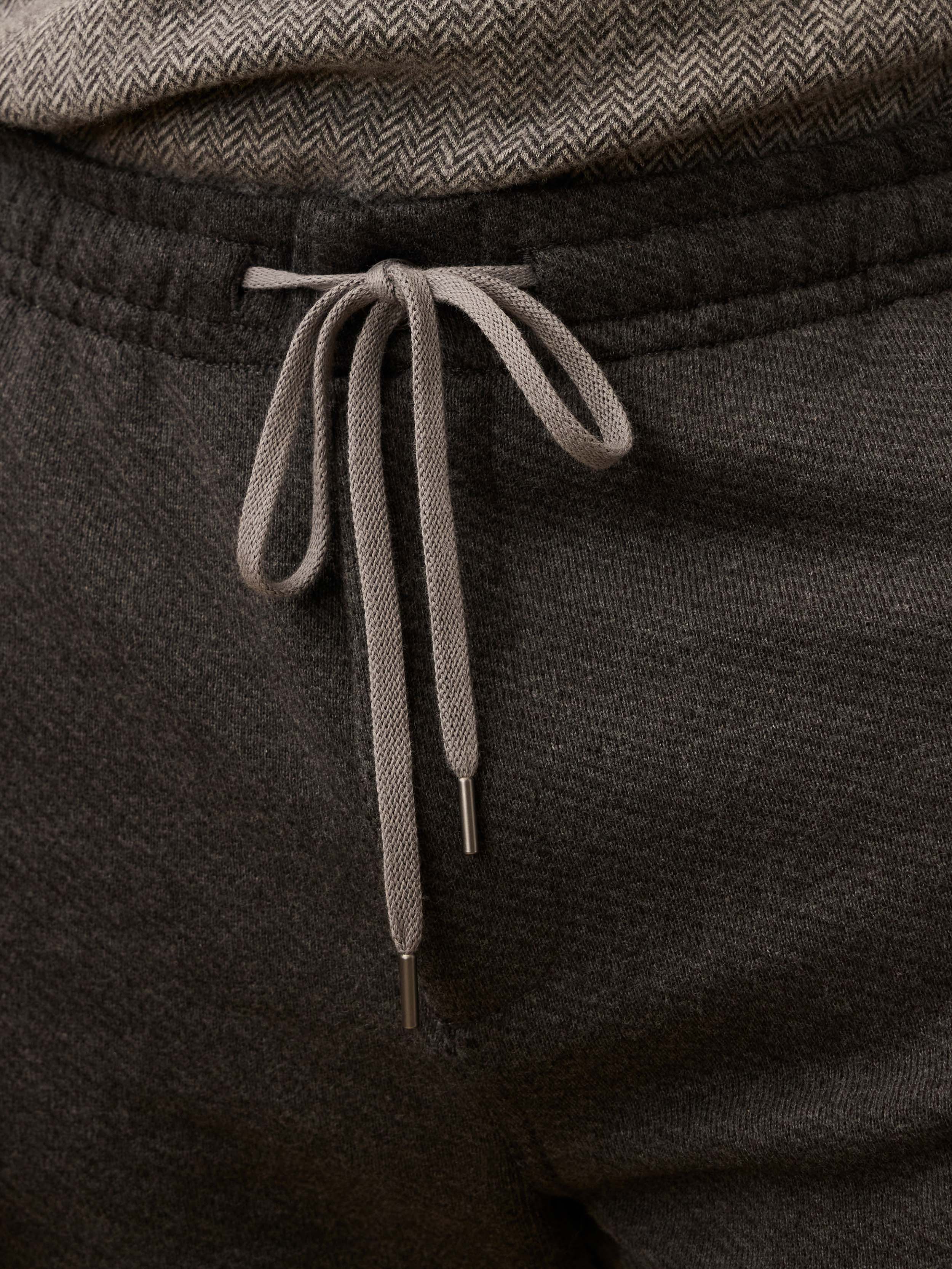 Dark gray sweatpants with a drawstring on a neutral background
