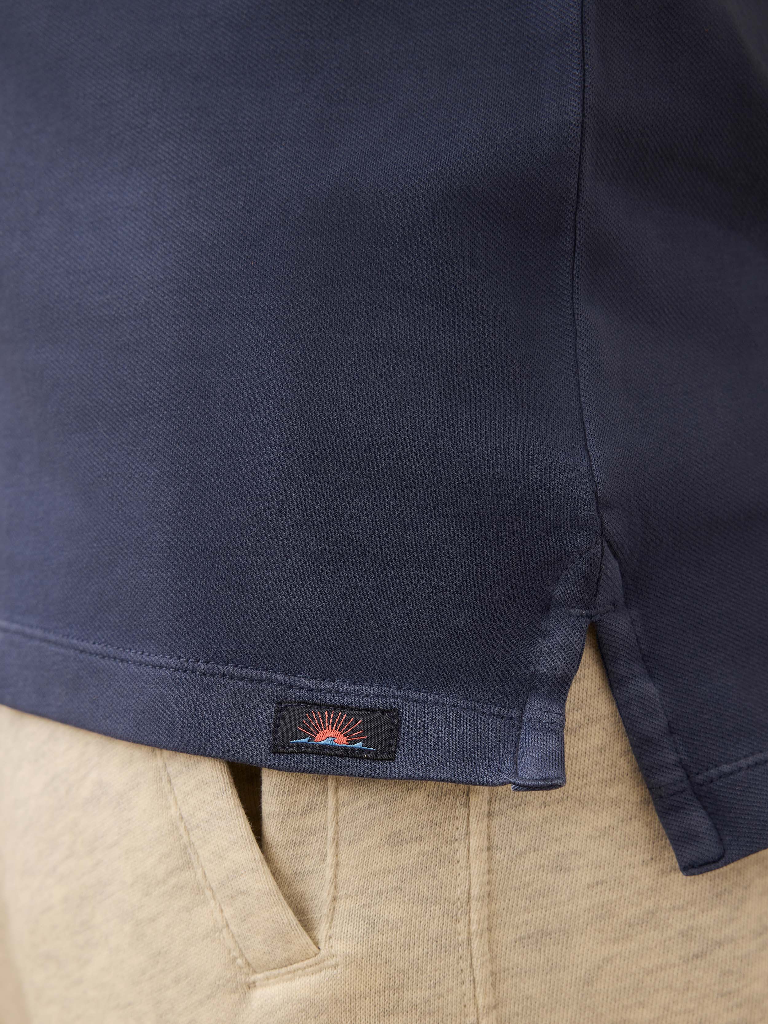 Navy blue shirt with a Faherty brand logo on the hem paired with heather grey sweatpants.