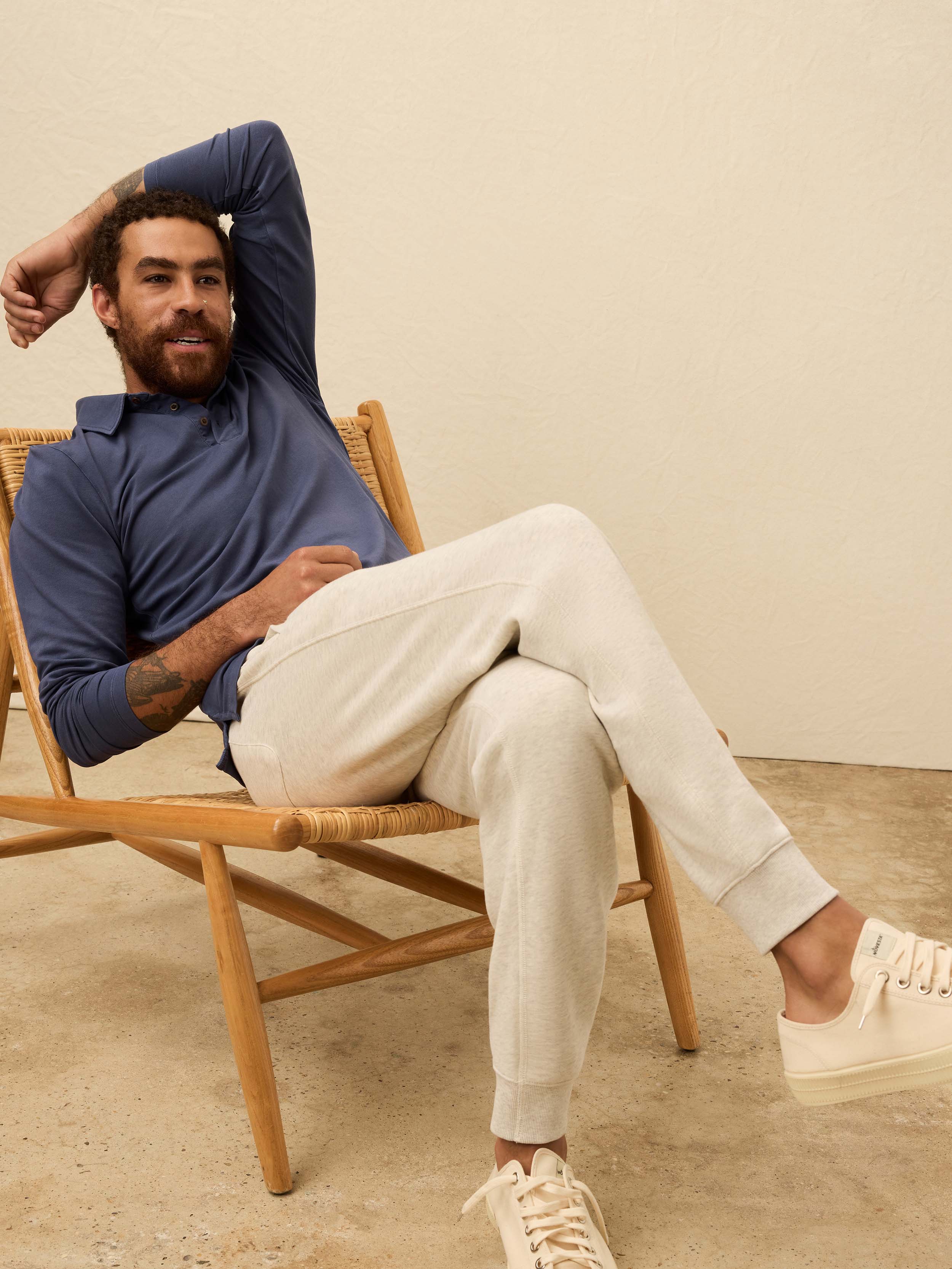 Man wearing a blue long-sleeve polo shirt against a beige background