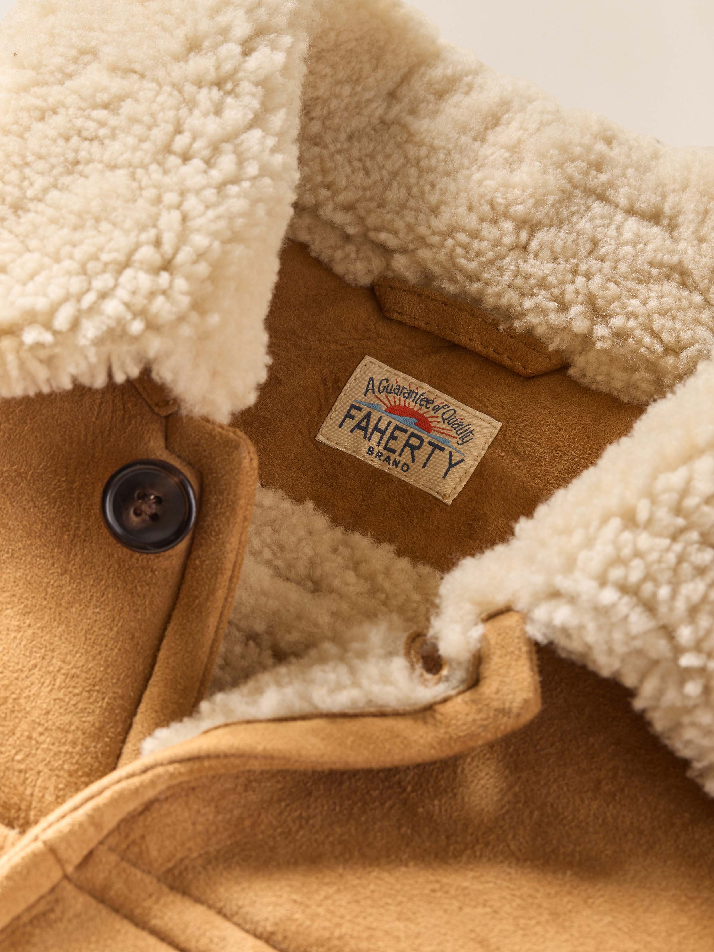 Close-up of a brown suede shearling jacket with white fleece lining and a visible 'Faherty' brand label.