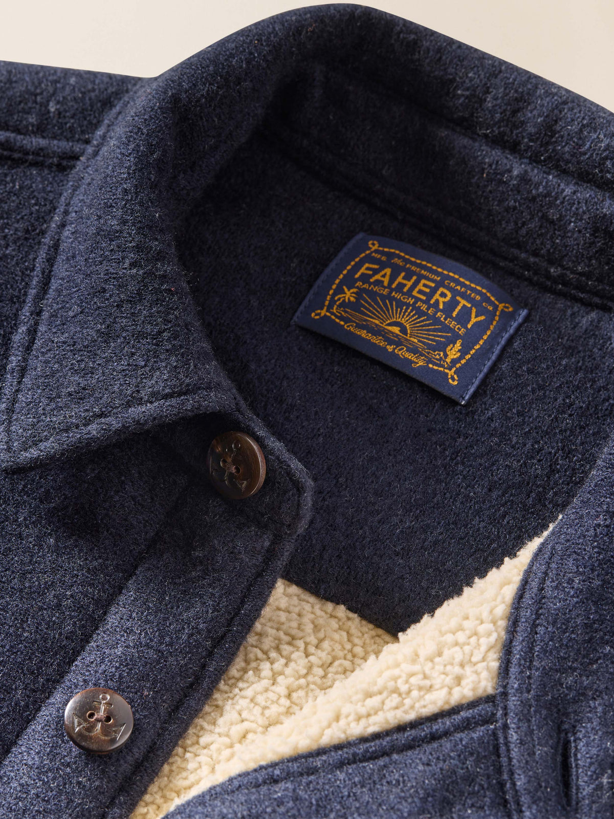 Close-up of a navy blue jacket with a Fajerty brand label on a beige background, image 5 of 6