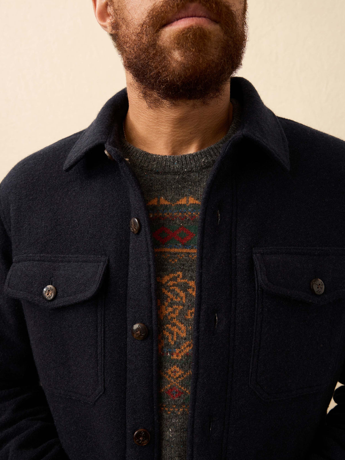 Man wearing a dark navy shirt jacket against a beige background, image 4 of 6