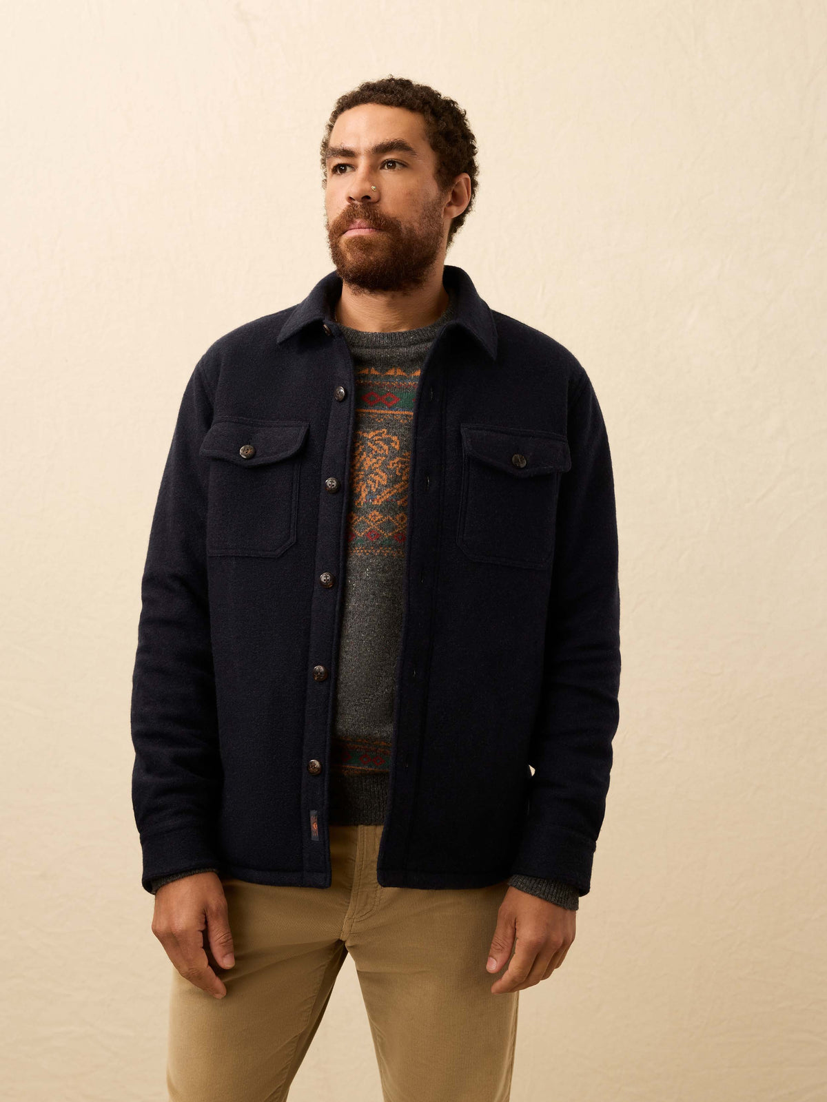 Man wearing a dark navy shirt jacket against a beige background, image 1 of 6