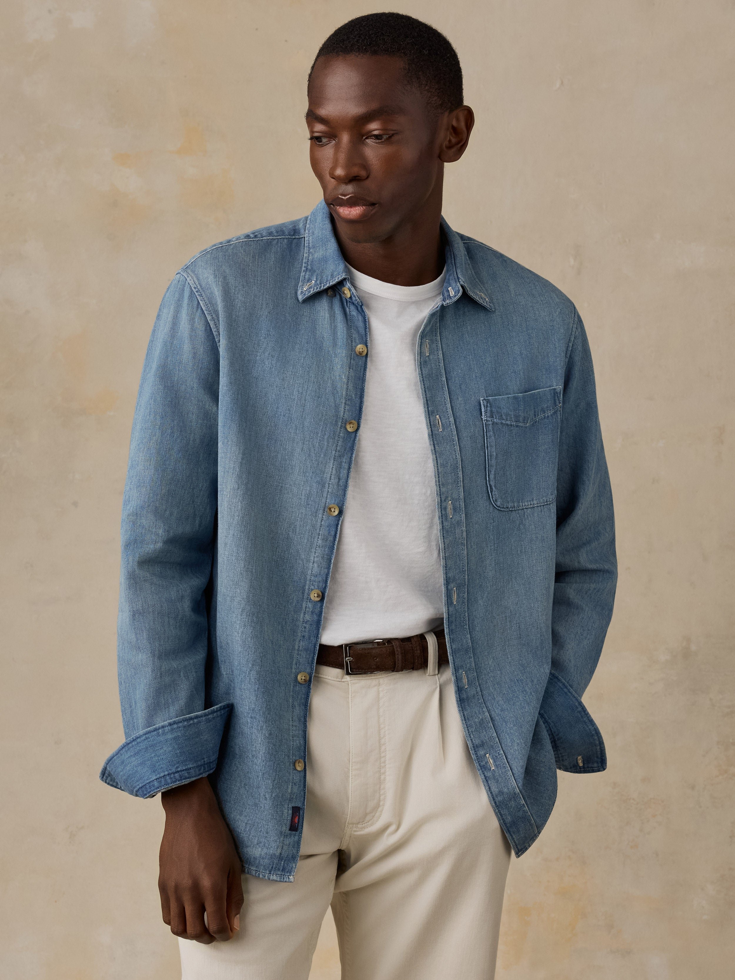 Man wearing a light blue denim shirt against a beige background
