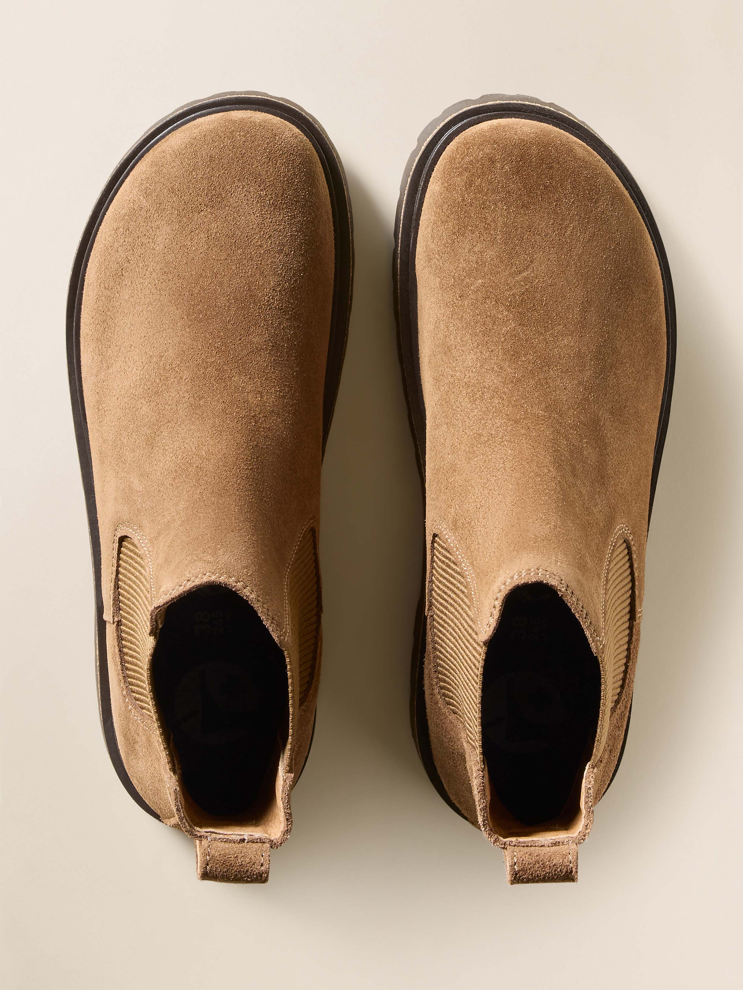 Pair of tan suede boots on a light beige background