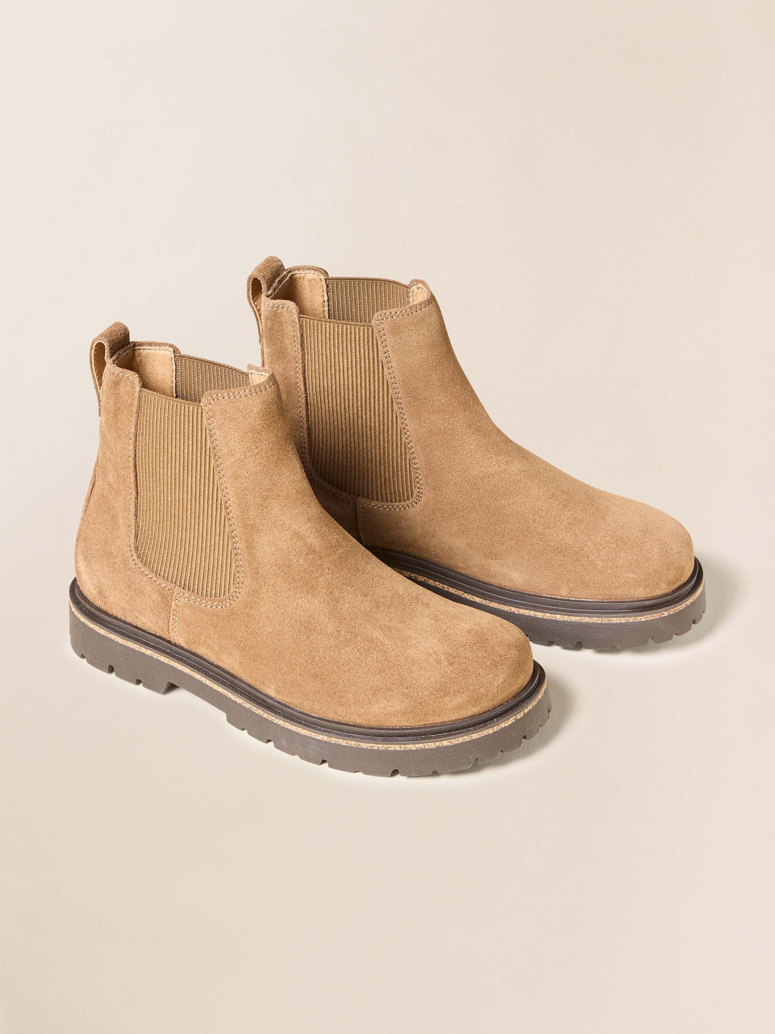Pair of tan Chelsea boots on a beige background