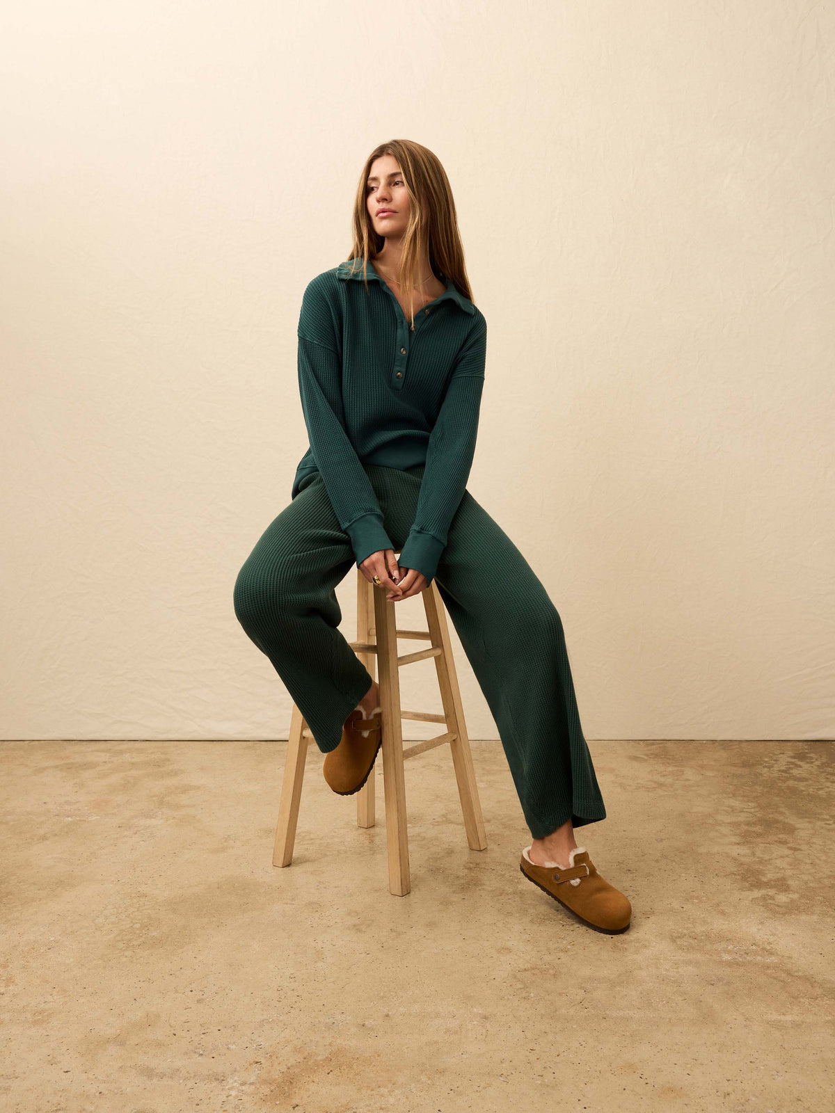 Woman is wearing green waffle pants with a matching henley long sleeve against a beige background, image 3 of 5