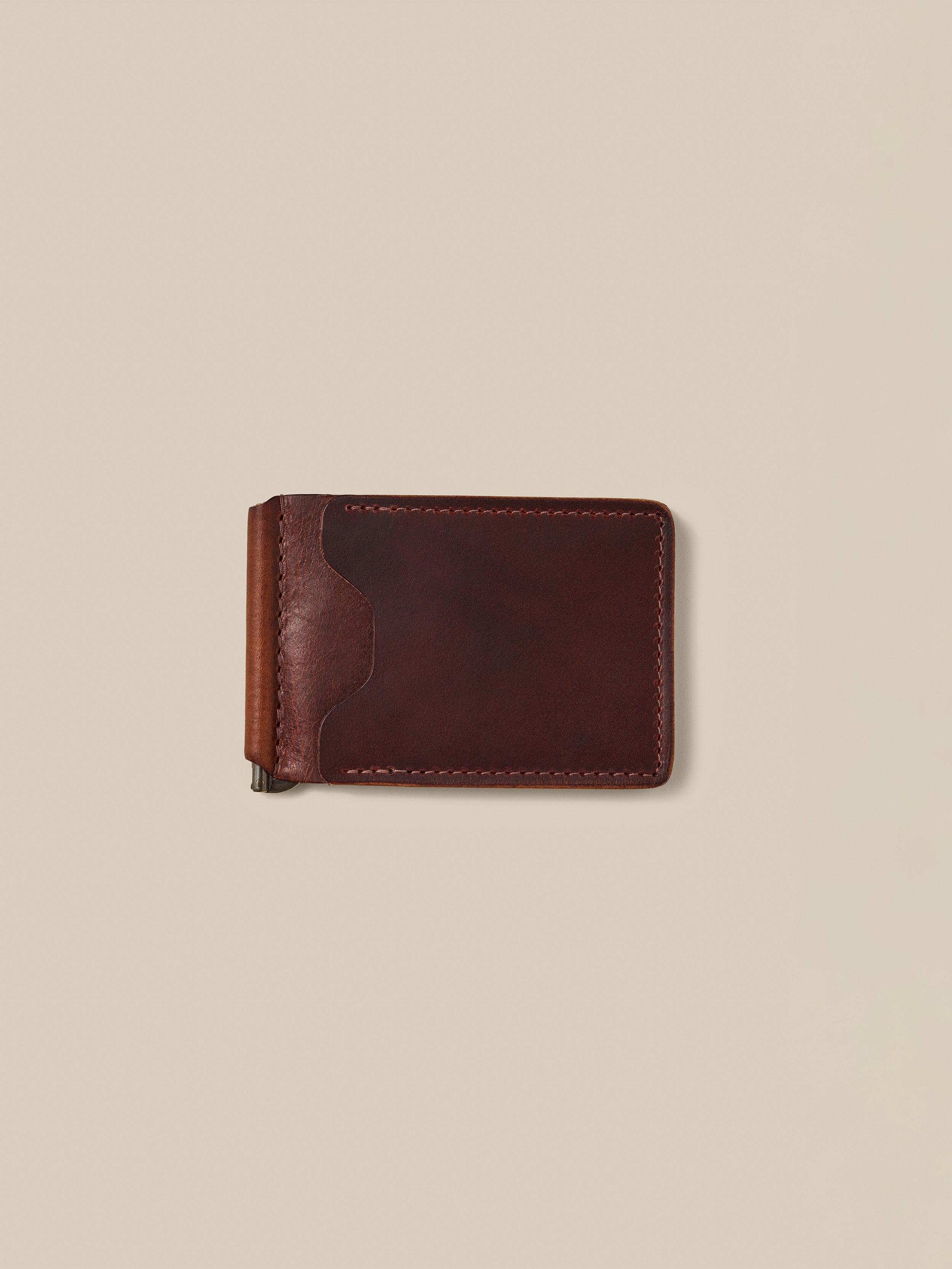 Brown leather money clip against a beige background