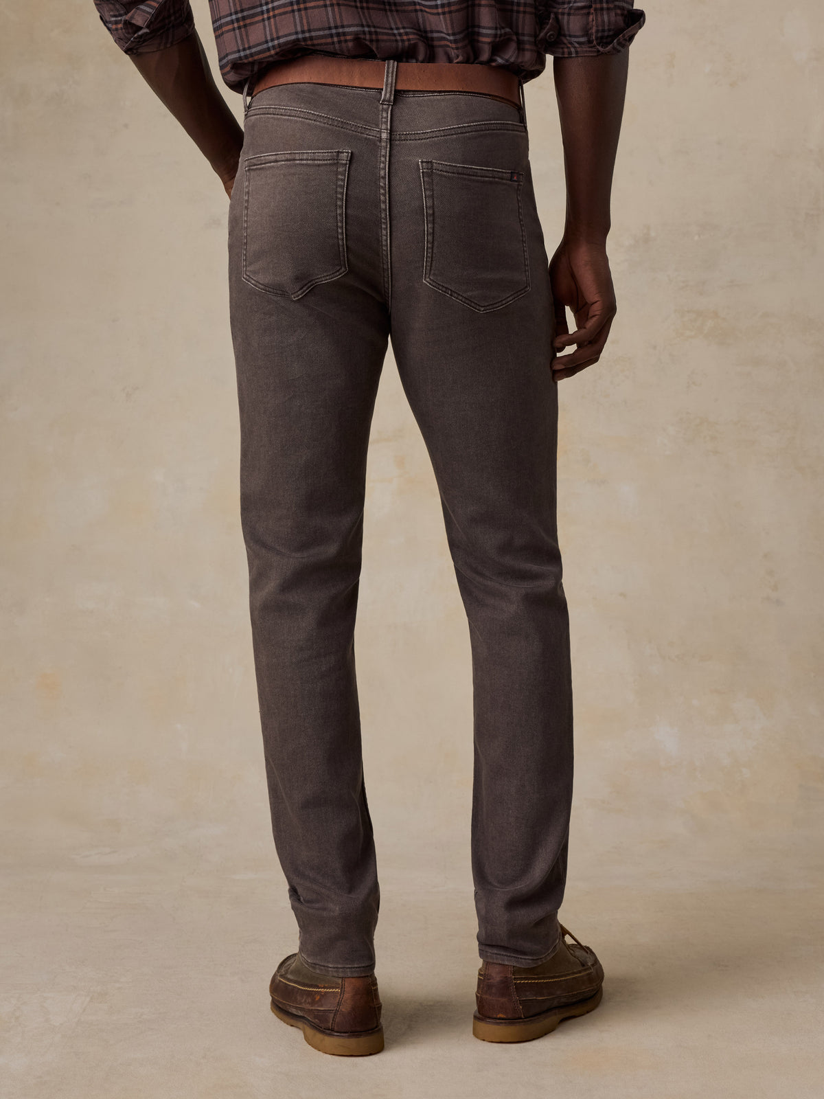 Man viewed from the back wearing a brown plaid shirt and brown pants, image 2 of 5